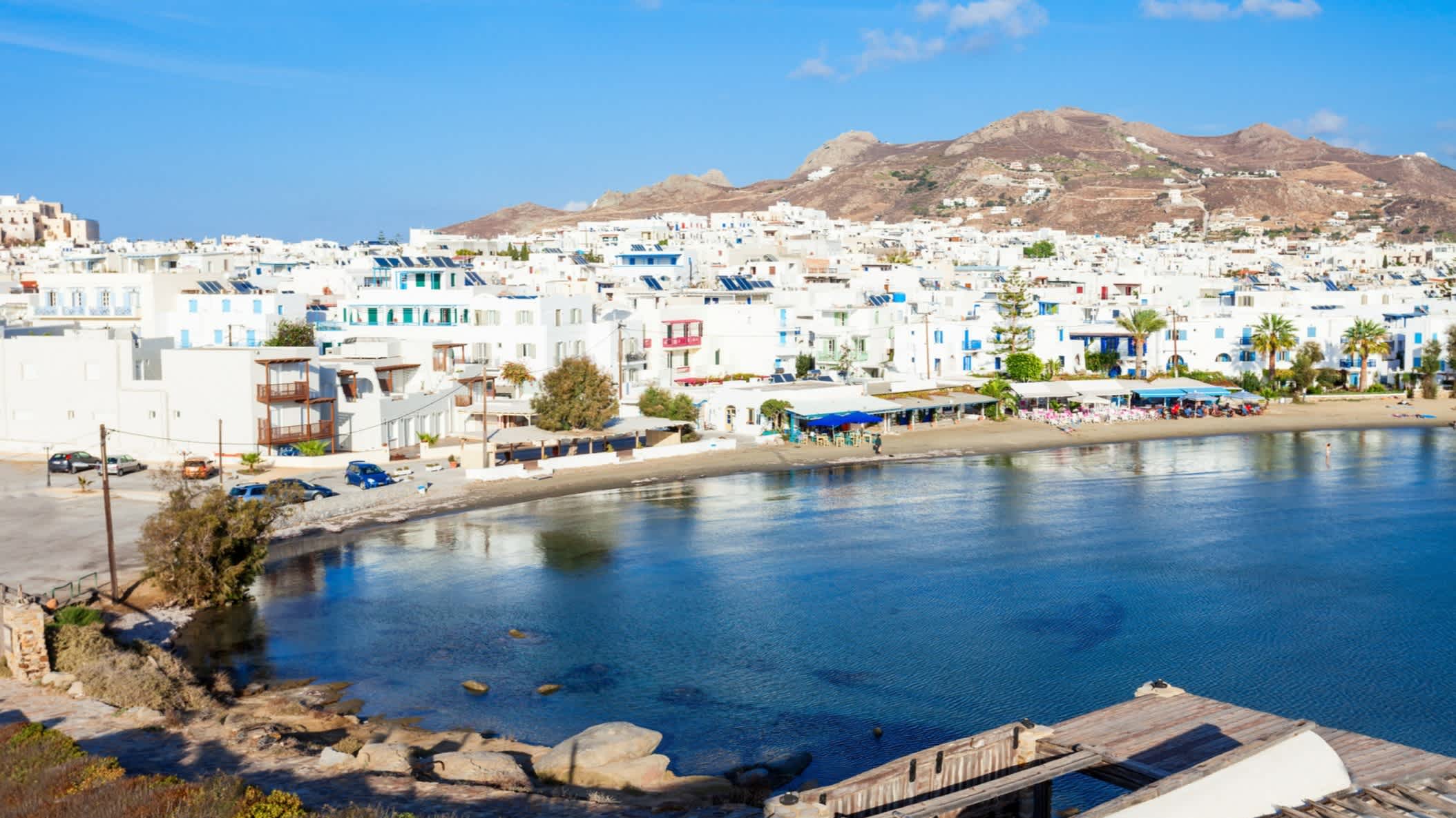 Blick auf den Strand Agios Georgios auf Naxos, Griechenland, mit den typischen weißen Häuserfassaden im Hintergrund.