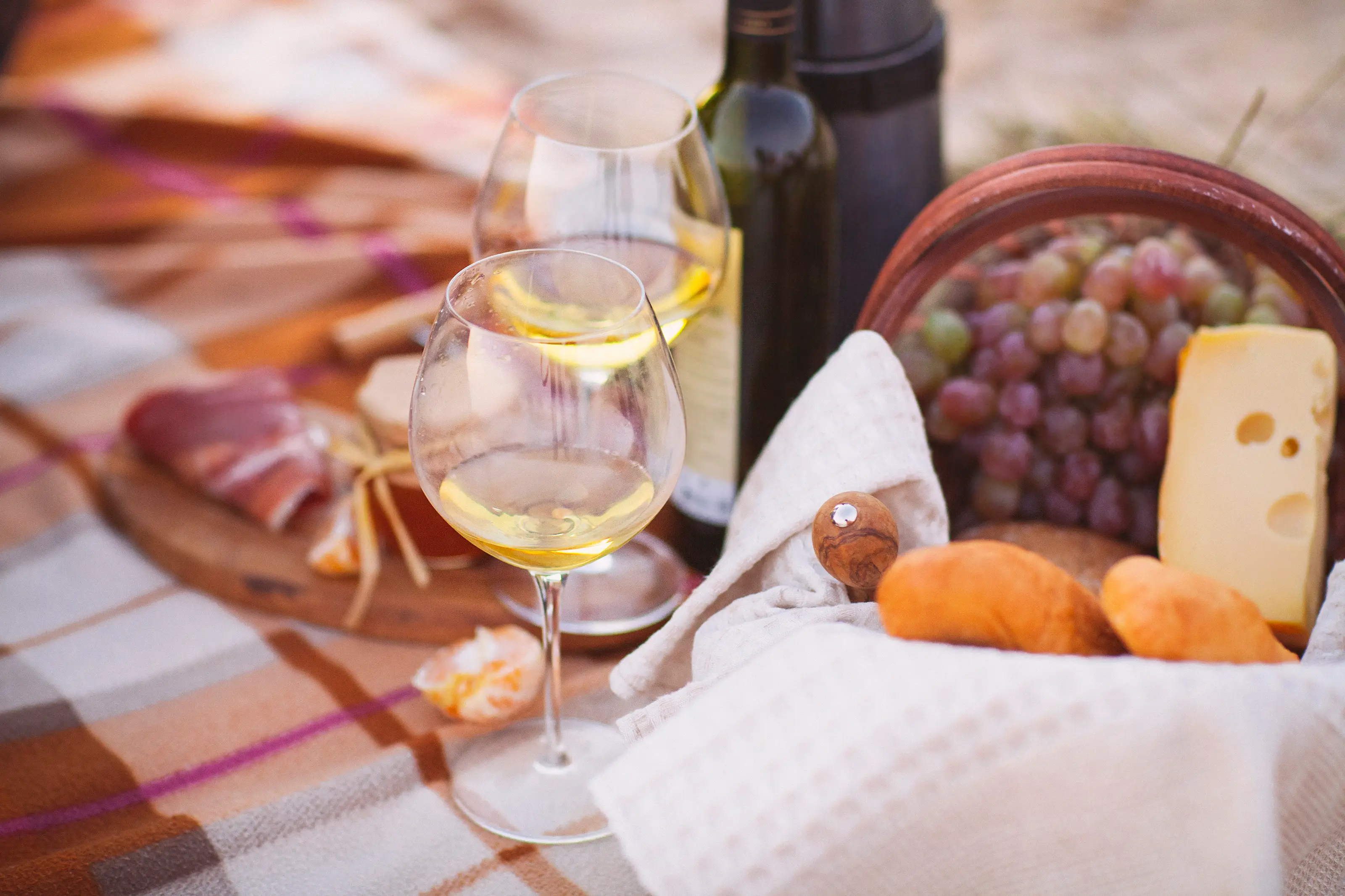 Weinfestival Picknick mit Weißwein, Trauben, Käse, Brot und Schinken auf einer Decke beim Weinfestival.