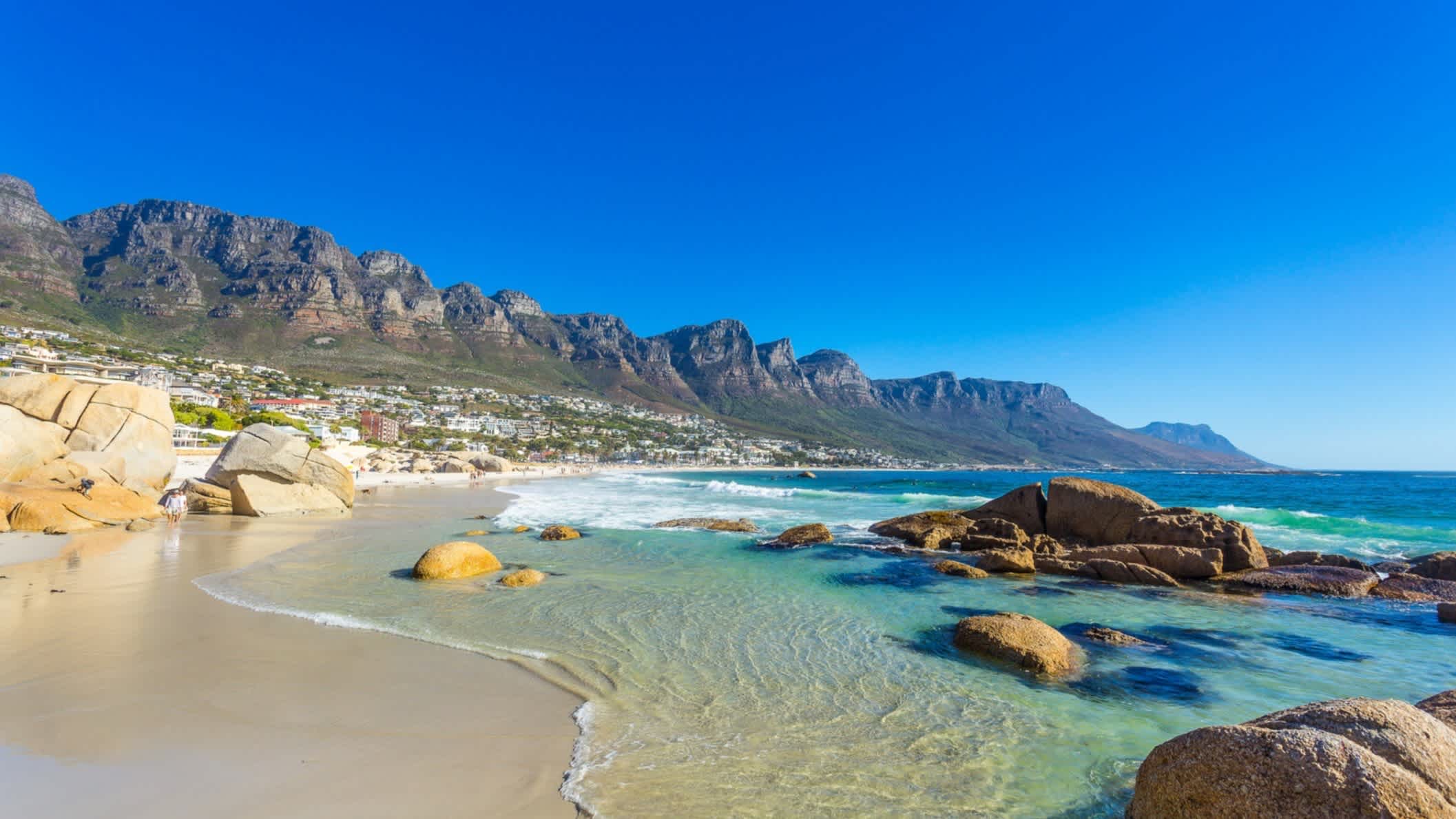 Clifton-Strand in Kapstadt mit den Zwölf Aposteln im Hintergrund bei strahlend blauem Himmel, Südafrika. 