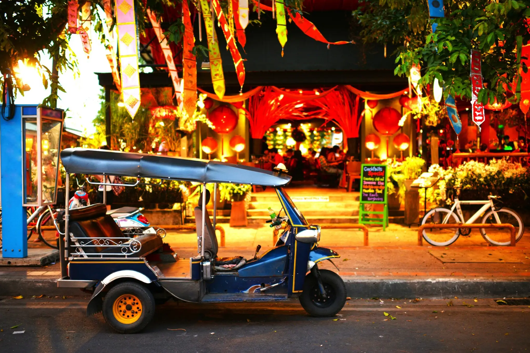 Thailand, Bangkok, Tuktuk Ein Tuktuk steht vor einem geschmückten Laden bei Nacht