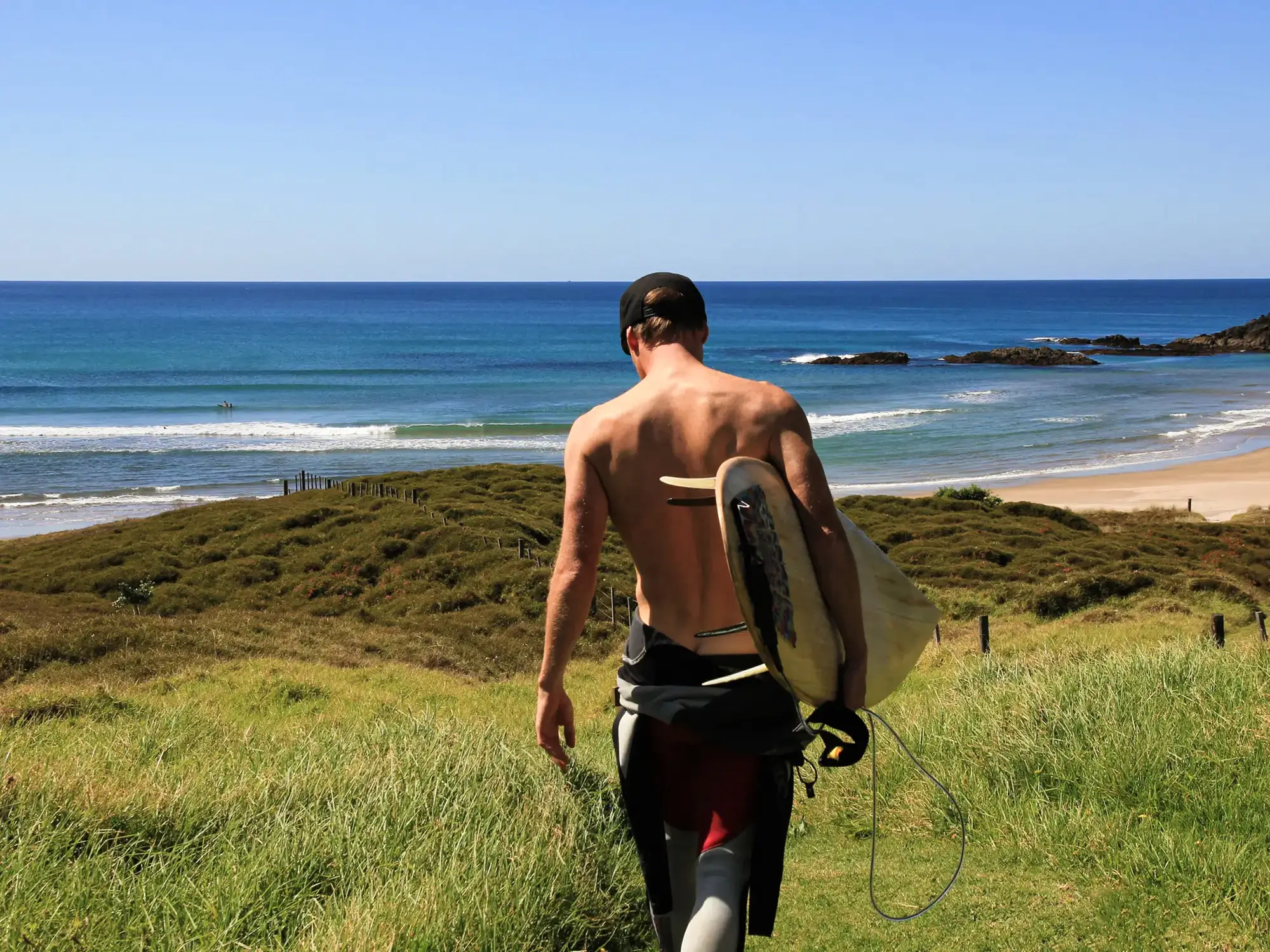Surfer mit Board auf dem Weg zum Strand. Raglan, Waikato, Neuseeland