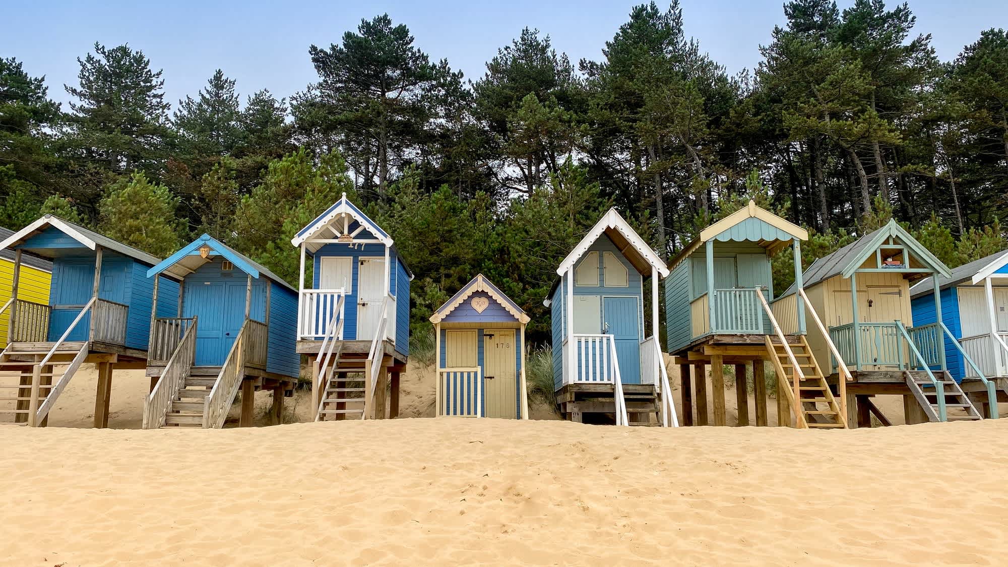 Strandhütten mit Pinienwälder im Hintergrund in Well-next-the-Sea Beach, Norfolk, England