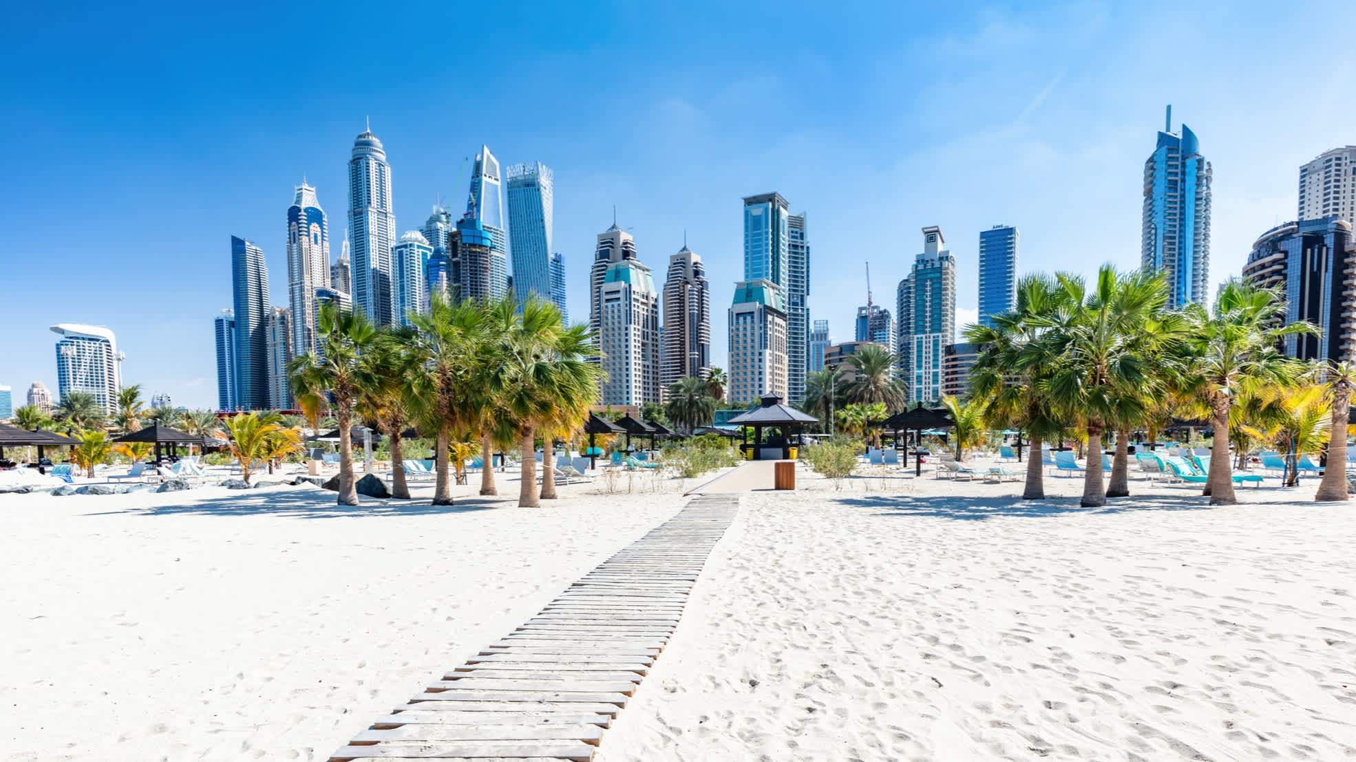 Dubais Skyline vom Strand mit Palmen aus gesehen