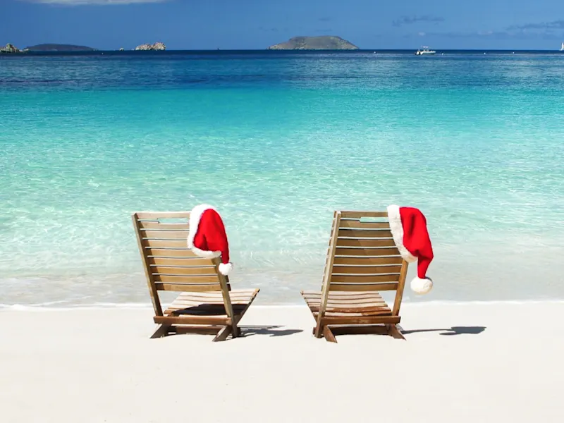 zwei leere Teakholzstühle mit Weihnachtshüten an einem Strand in St.John, US Virign Islands

