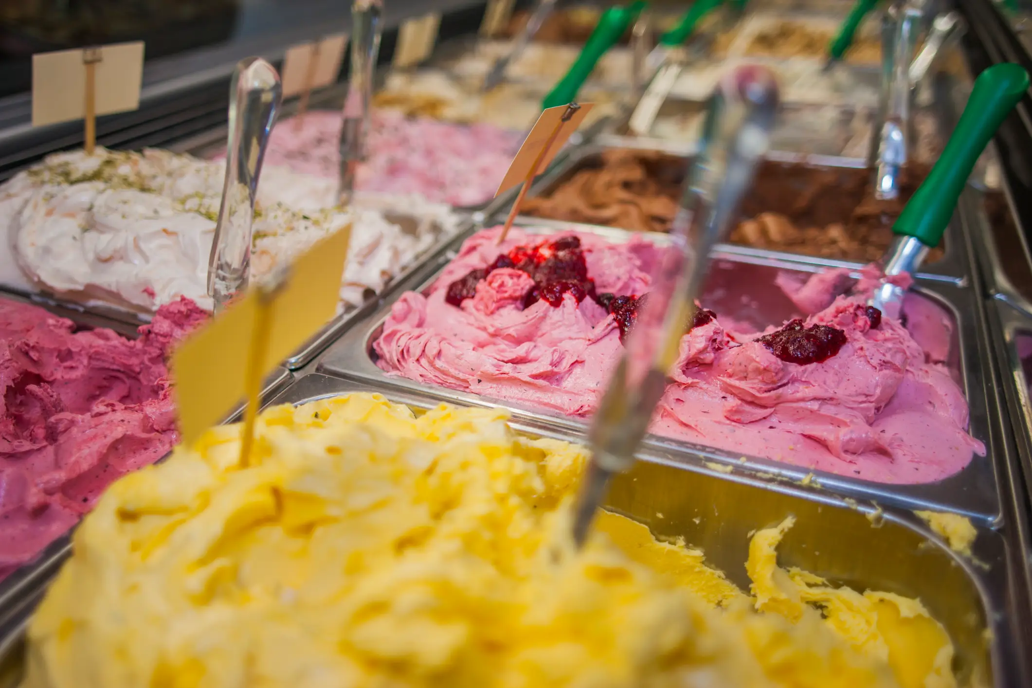 Eis Nahaufnahme verschiedener Sorten Gelato in einer Eistheke mit farbigen Schaufeln.