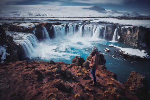Ein Mann steht vor dem Wasserfall Godafoss in Island