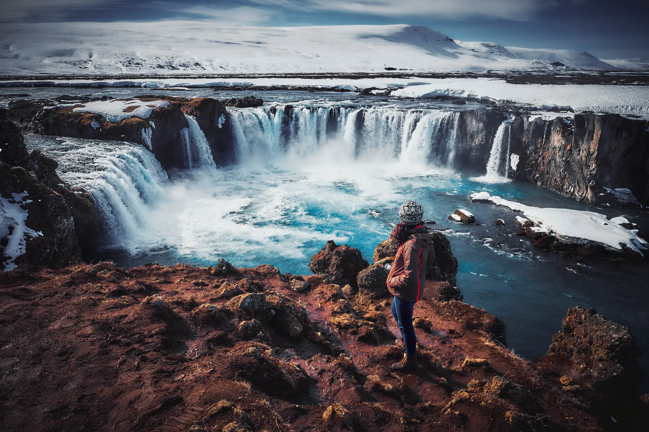 Ein Mann steht vor dem Wasserfall Godafoss in Island