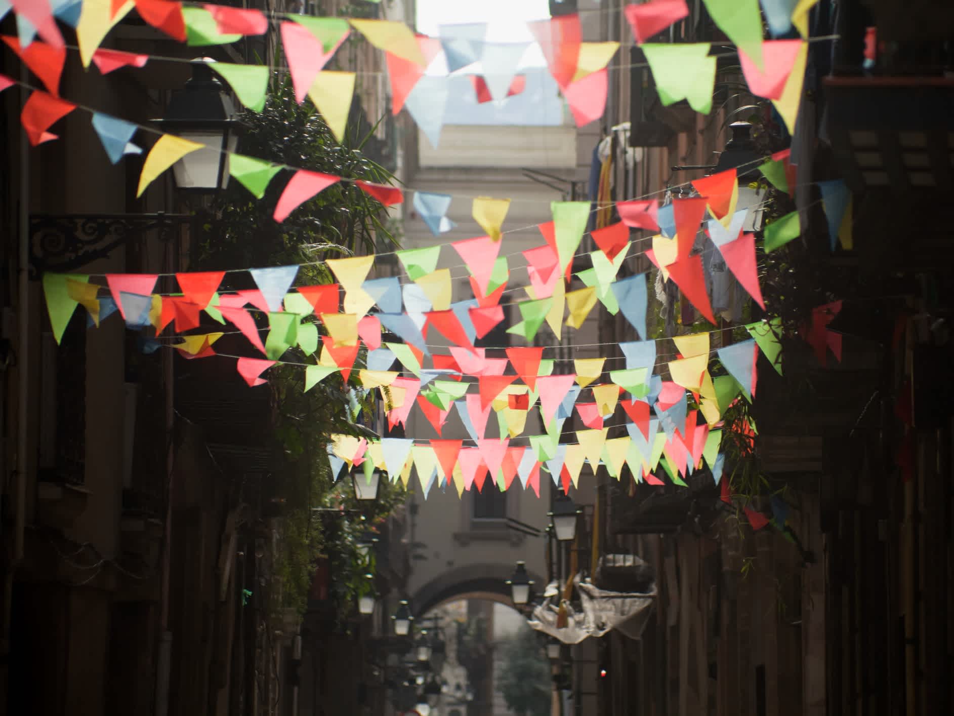 Mehrfarbige Dekorationen in einer schmalen Straße, Barcelona, Spanien. 