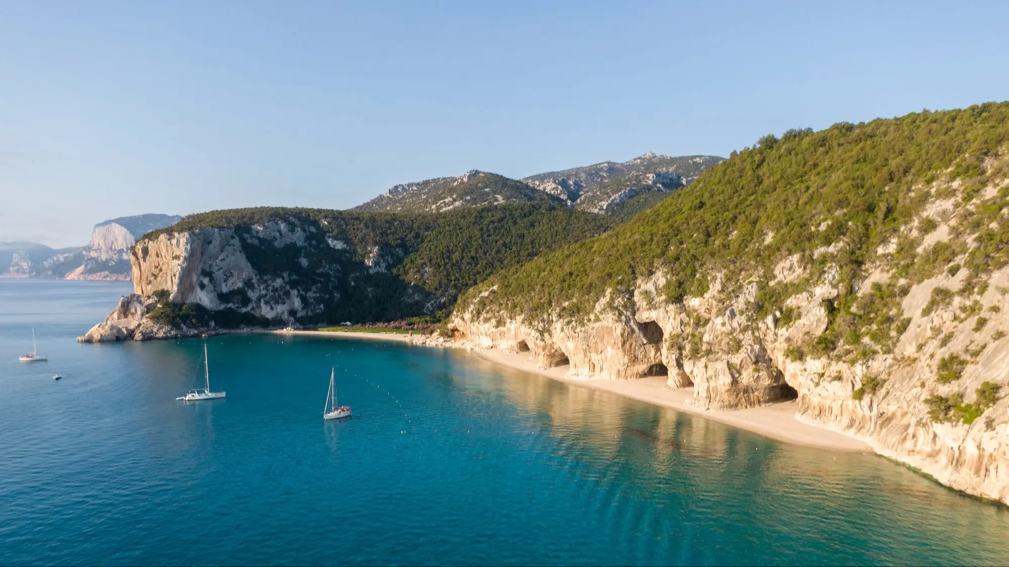 Italien, Sardinien, Cala Luna Blick aus der Luft auf die Höhlen von Cala Luna Strand, Sardinien, Italien sowie das Meer, die Steilküsten und Booten im Meer.
