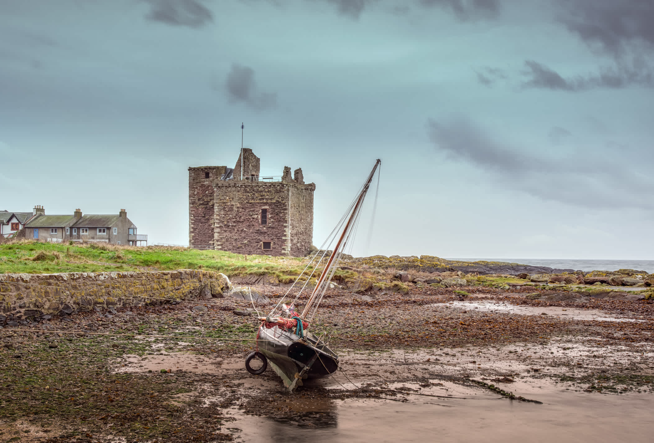 Le vieux château de Portencross et un yacht couché sur le côté à marée basse, dans le North Ayrshire en Écosse.