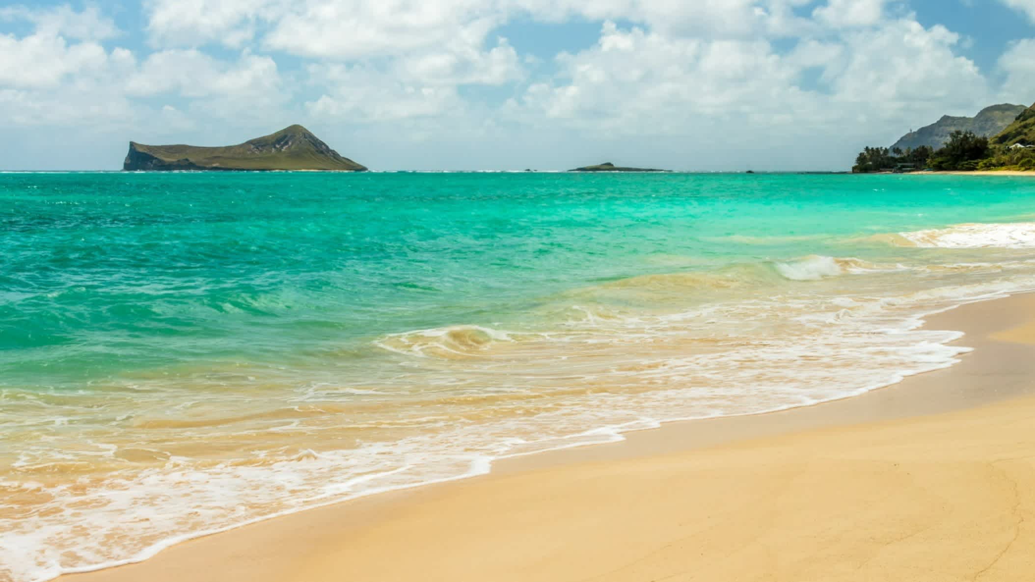 Der Strand Waimanalo Bay, Oahu, Hawaii, USA bei klarem Wetter und mit Blick auf das türkise Meer sowie einer vorgelagerten Insel in der Bucht.