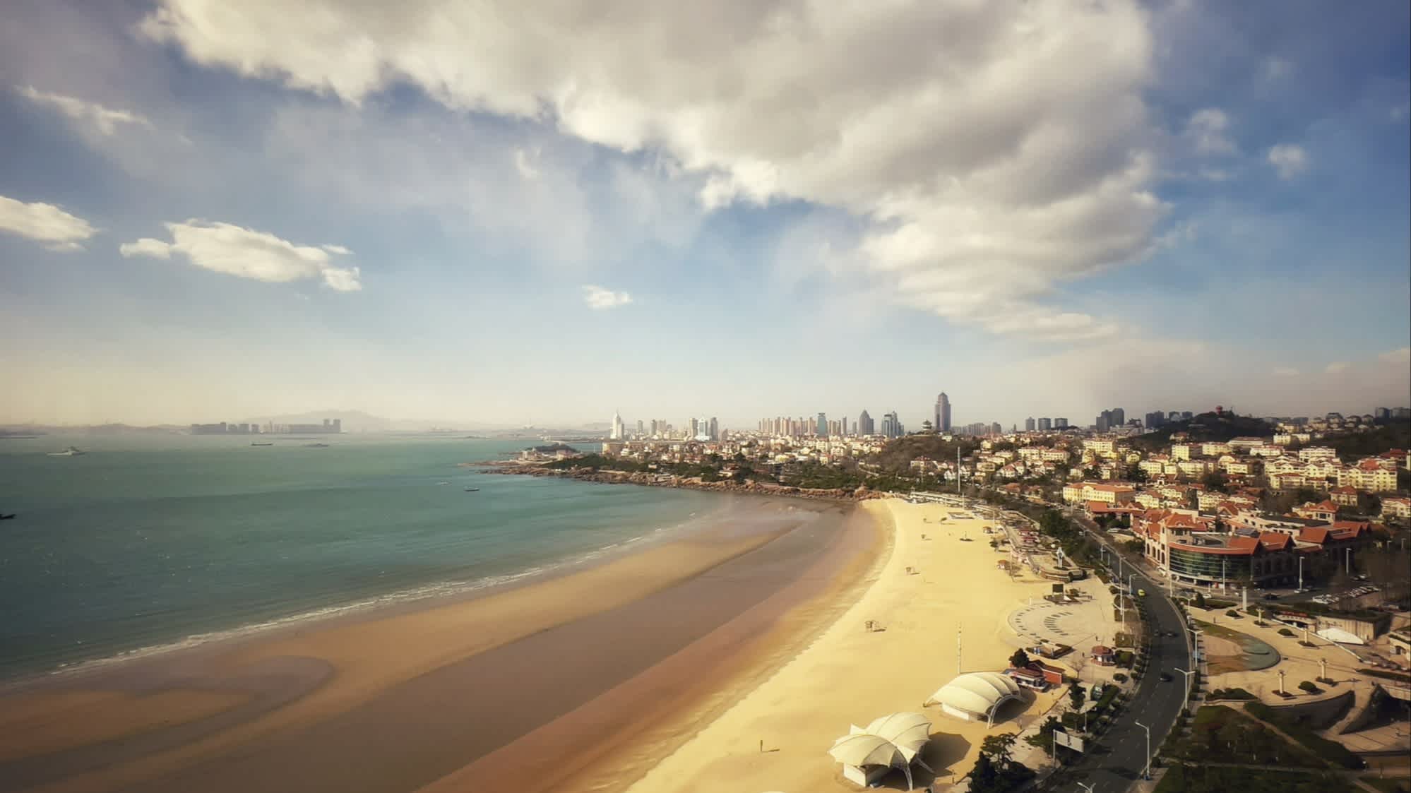 Aussicht auf den Qingdao No.1 Buche, China bei Dämmerung sowie mit Ausblick auf die bebaute Küste.

