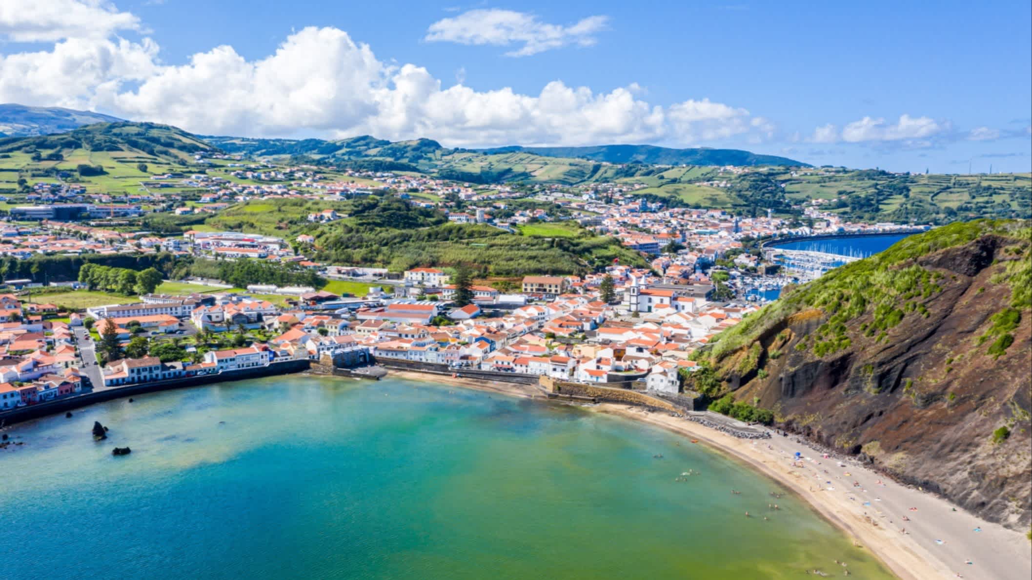 Luftaufnahme der Bucht Baia do Porto Pim, Azoren, Portugal bei sonnigem Wetter und mit Ausblick über die Stadt und die Klippen.