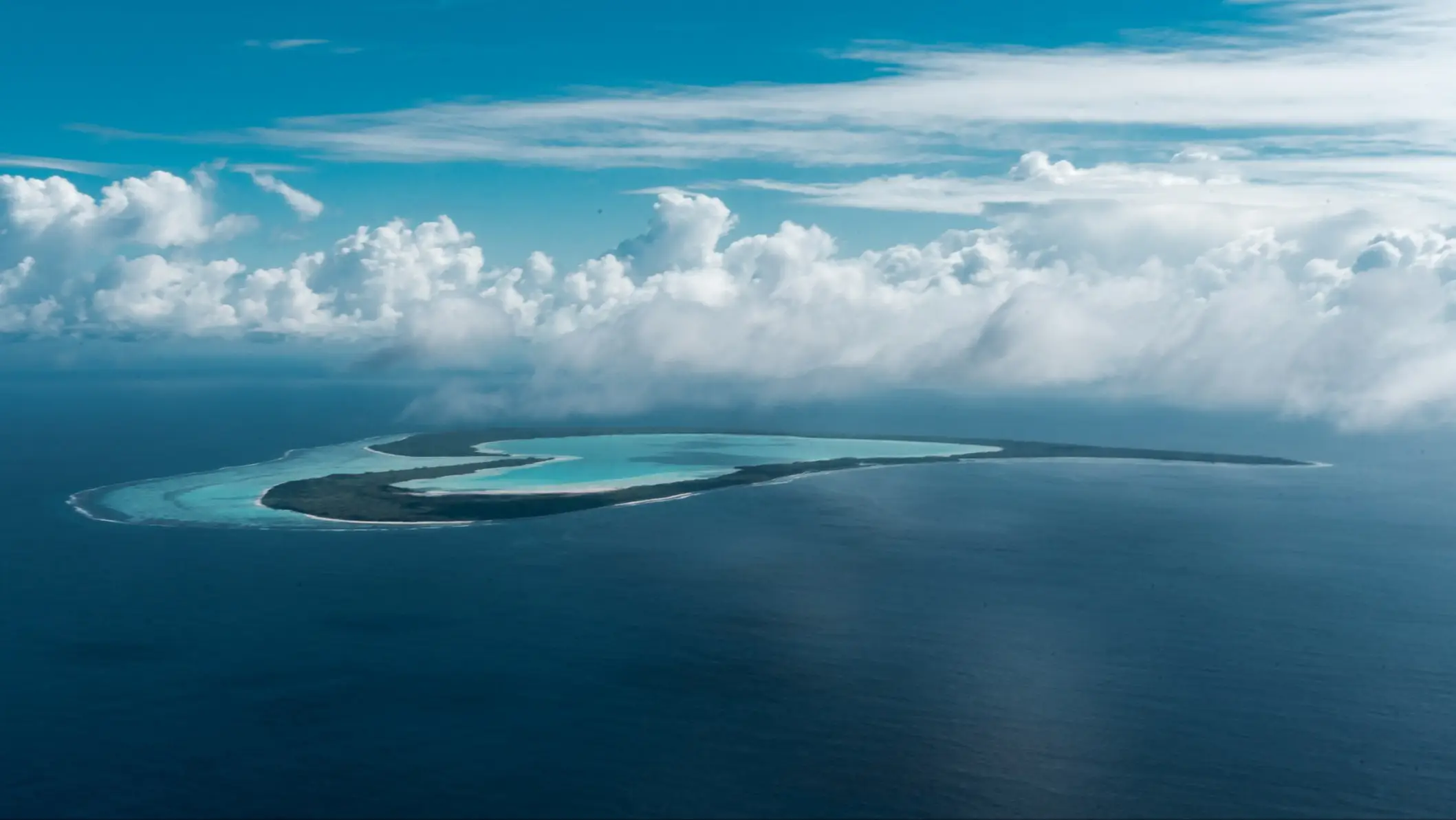 Vue aérienne de l'atoll de Tupai en forme de cœur, avec lagon turquoise entouré par l'océan, Polynésie Française.