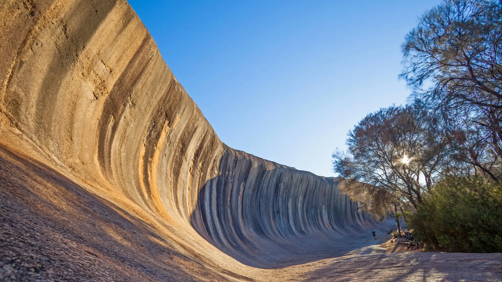 Une femme se tient au milieu de Wave Rock, près de la ville de Hyden, en Australie occidentale.
 