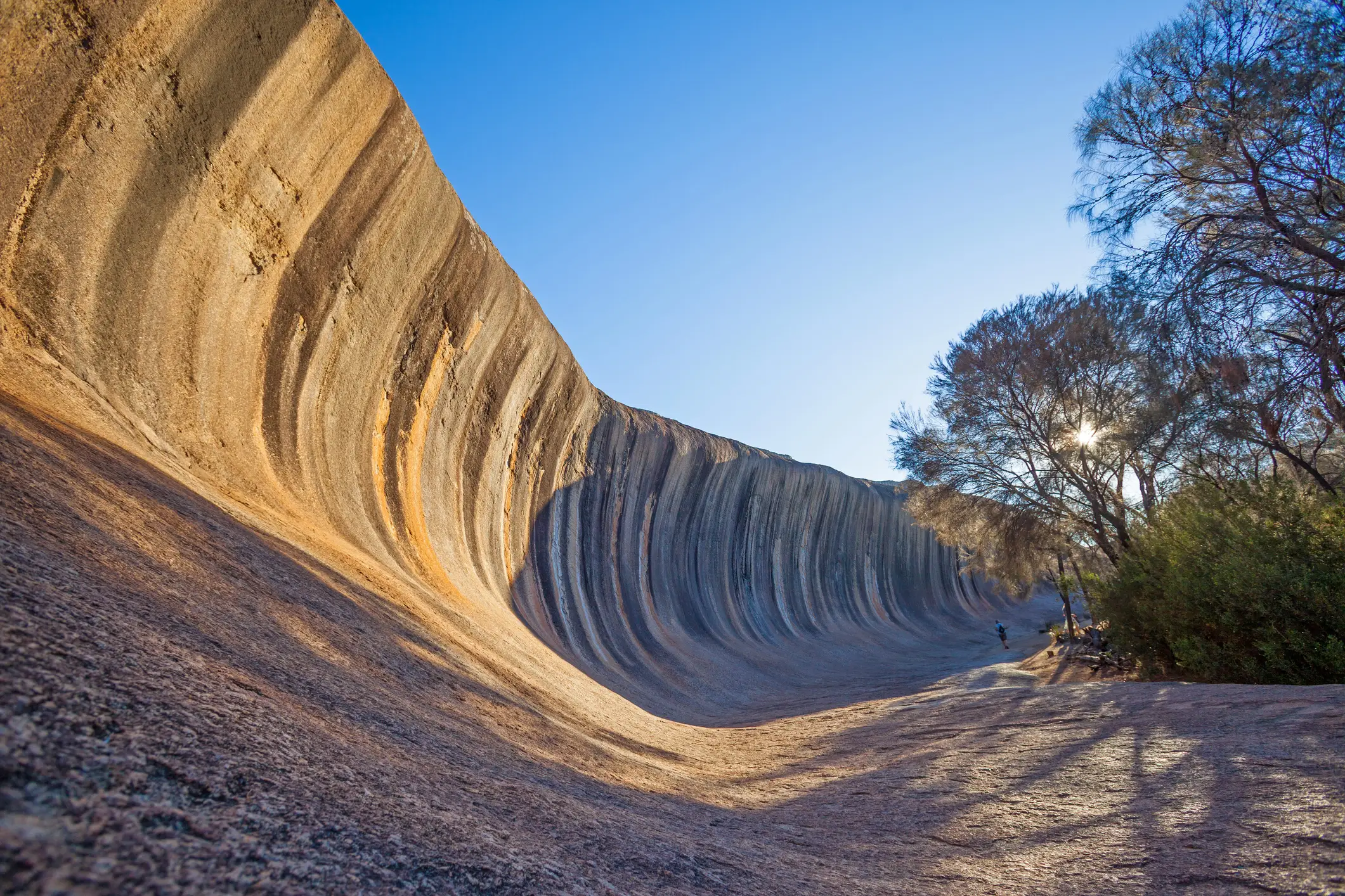 Une femme se tient au milieu de Wave Rock, près de la ville de Hyden, en Australie occidentale.
 