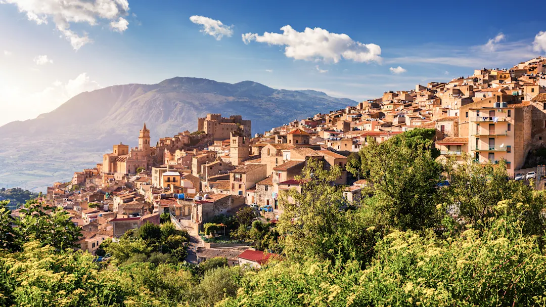 Historische Stadt auf einem Hügel mit Bergen im Hintergrund. Caccamo, Sizilien, Italien.