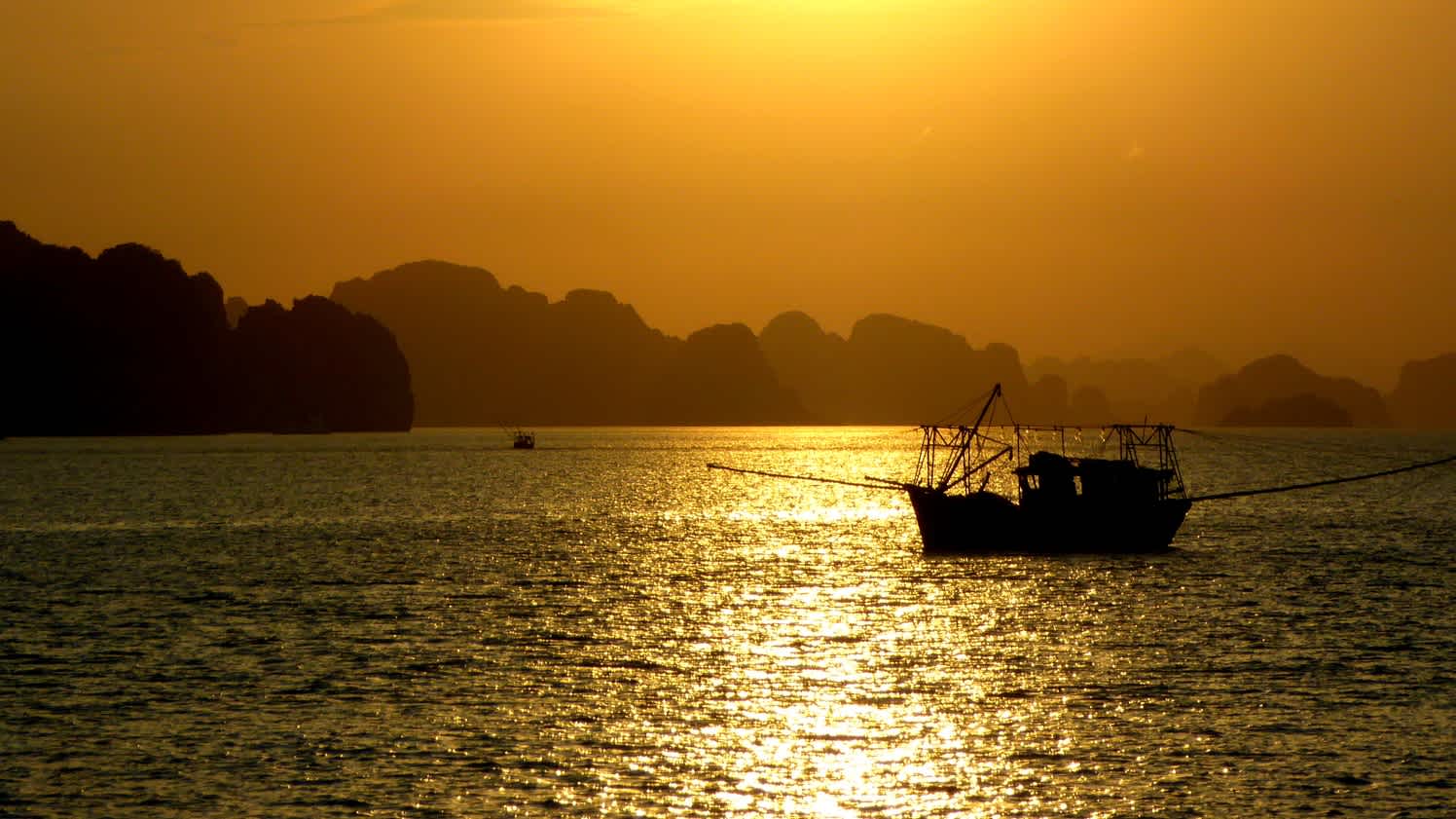 Bateau sur l'eau dans la baie de Bai Tu Long, Vietnam au coucher du soleil