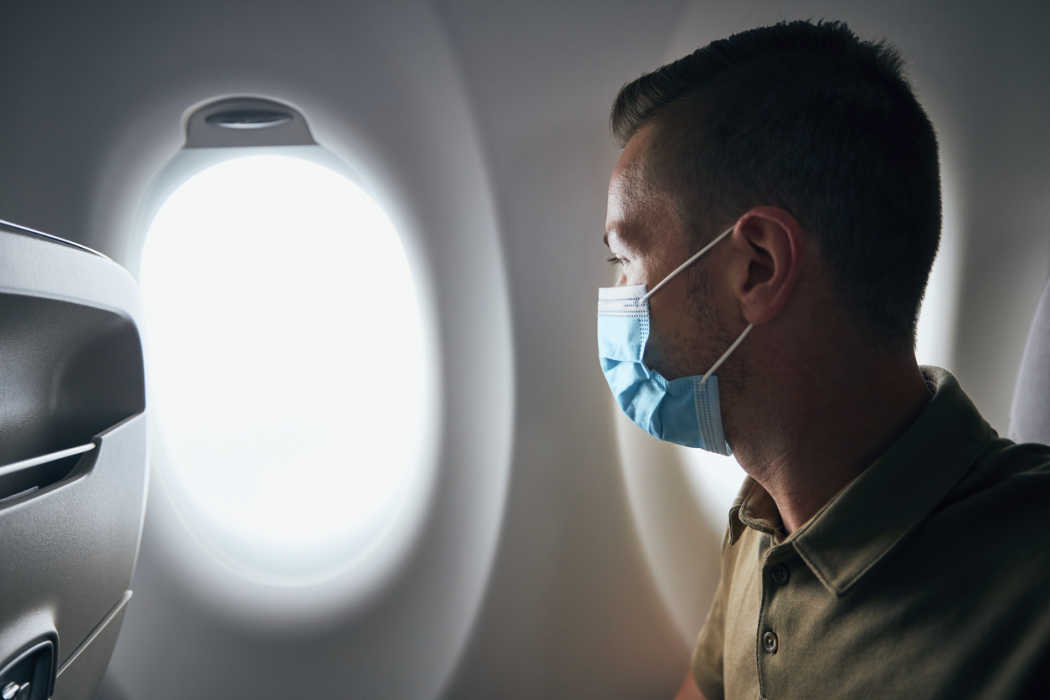 Un voyageur assis côté hublot dans un avion. Etude Tourlane – Comment organiser un voyage en 2021.
