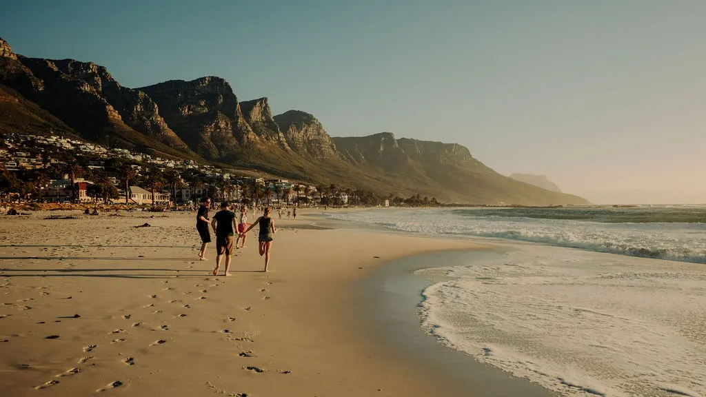Voyagez avec Tourlane, femme au manteau rouge faisant face à la mer.