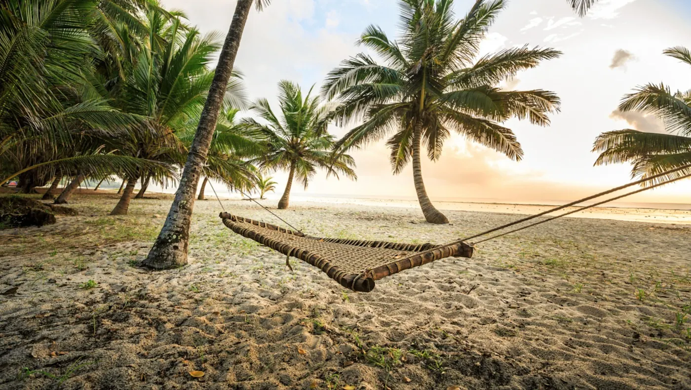 Kenia, Diani Beach, Kwale Hängematte am Strand mit Palmen bei Sonnenuntergang. Diani Beach, Kwale, Kenia.