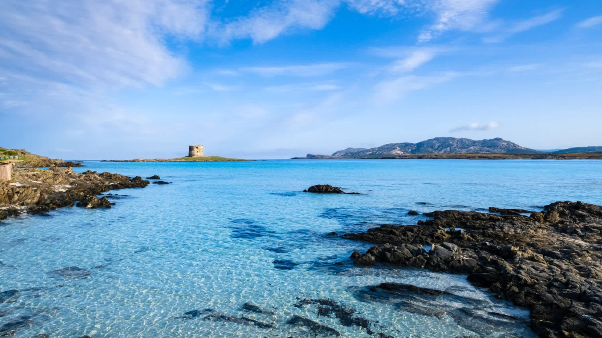 Blick vom Strand La Pelosa, Sardinien, Italien auf das Meer mit einer vorgelagerten Insel sowie einer Festung.