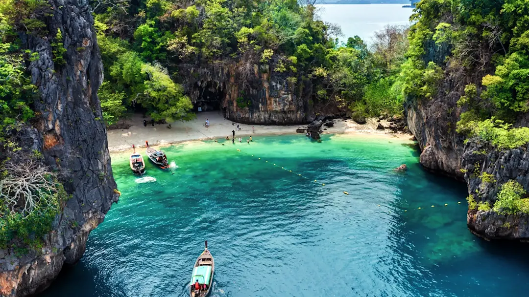 Boote in einer türkisfarbenen Lagune umgeben von Felsen. Krabi, Südthailand, Thailand.