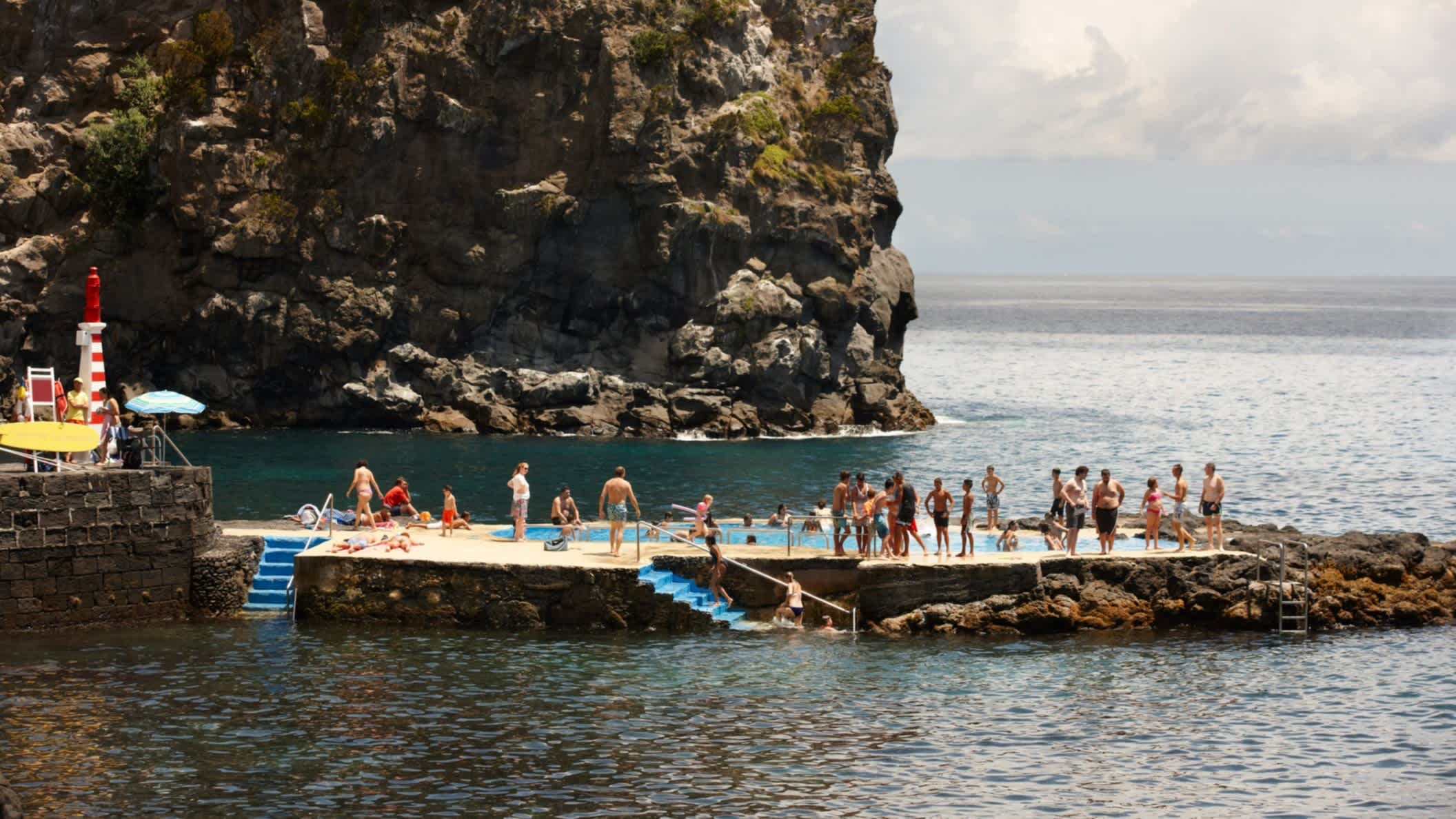 Natürliches Schwimmbad mit Menschen am Pool im Atlantischen Ozean in Caloura, Sao Miguel, Azoren, Portugal.

