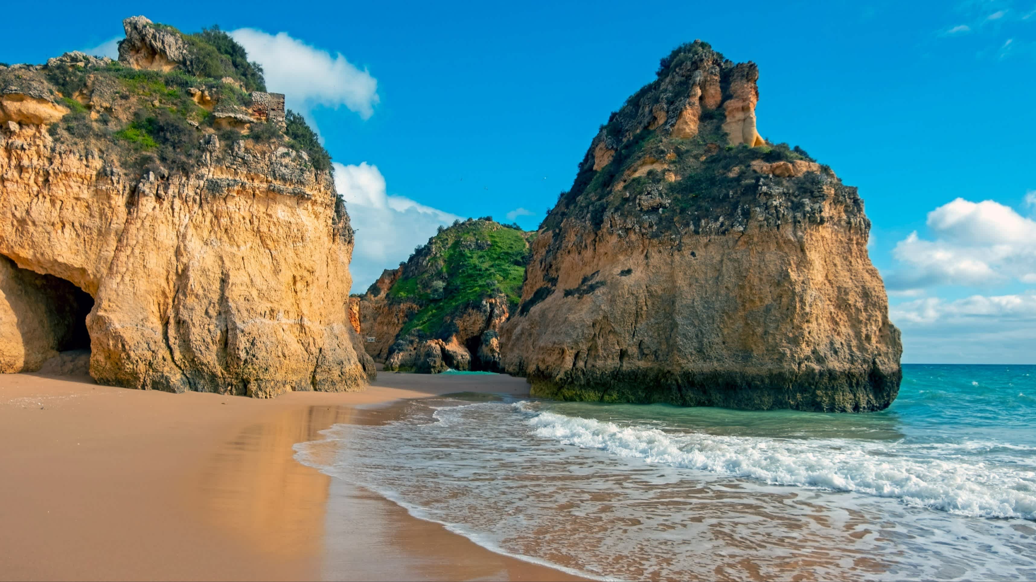Riesige Felsen an der Küste von Praia Tres Irmaos, Alvor, Algarve Portugal bei Sonnenschein.