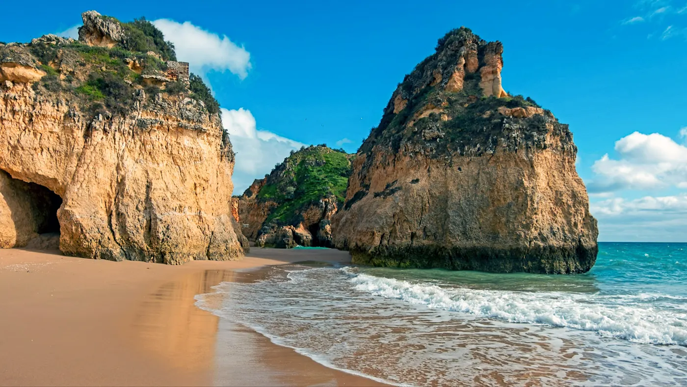 Riesige Felsen an der Küste von Praia Tres Irmaos, Alvor, Algarve Portugal bei Sonnenschein.