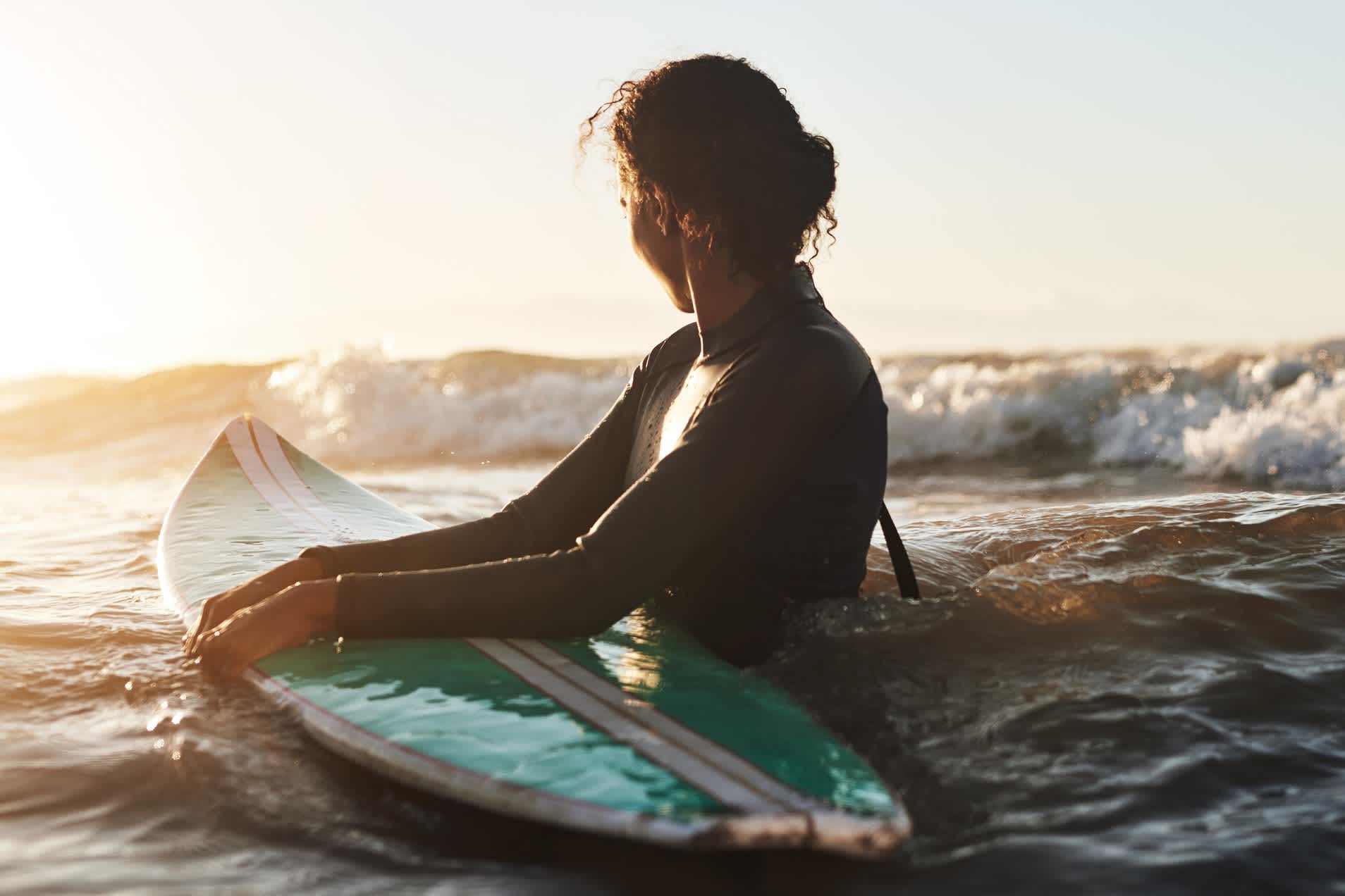 Frau mit einem Surfbrett im Meer in Afrika.
