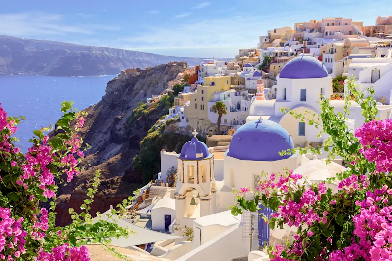 White-blue churches and flowers with sea view, Oia, Santorini, South Aegean, Greece.