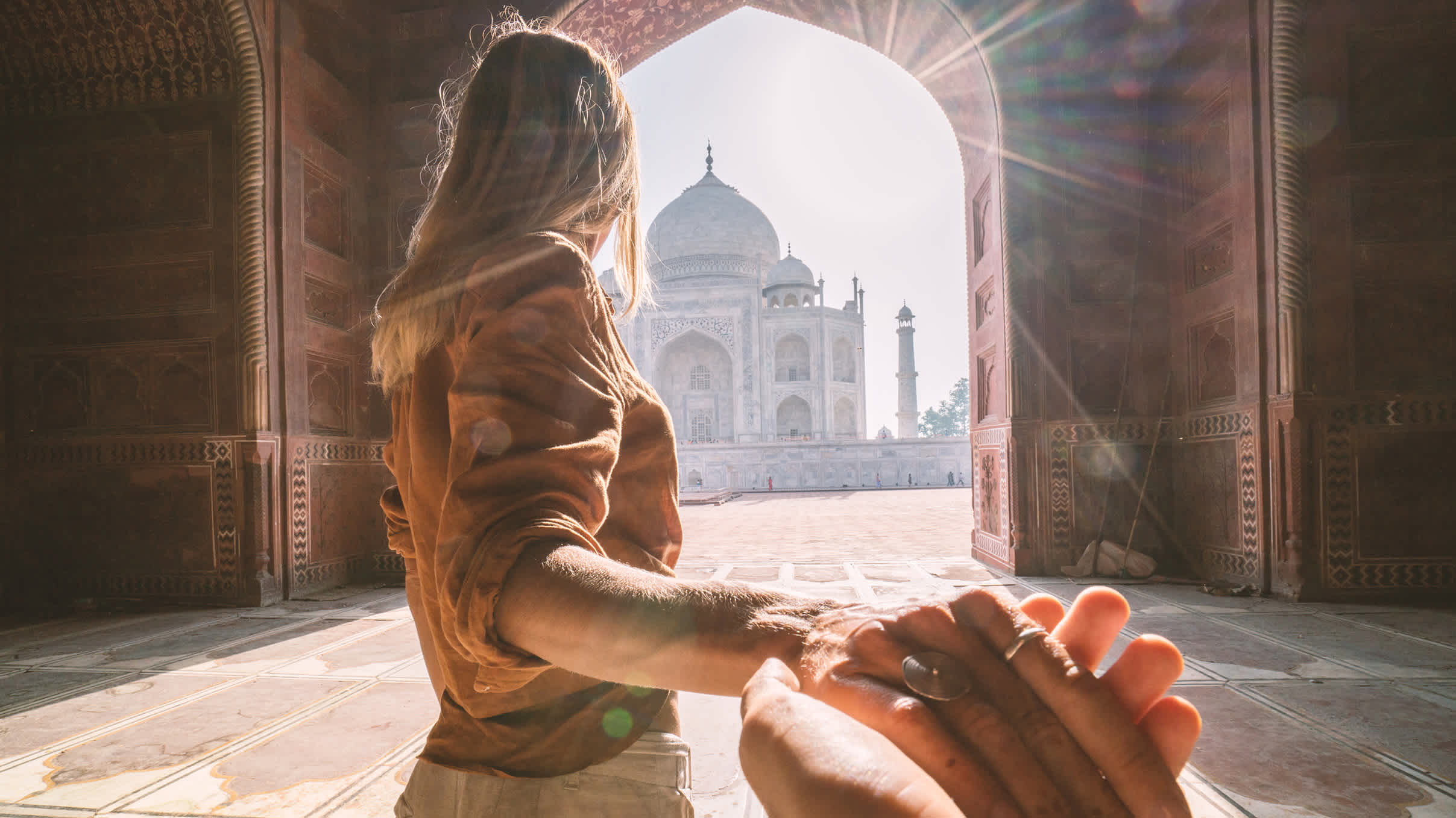 Frau führt Mann in den Taj Mahal in Indien.