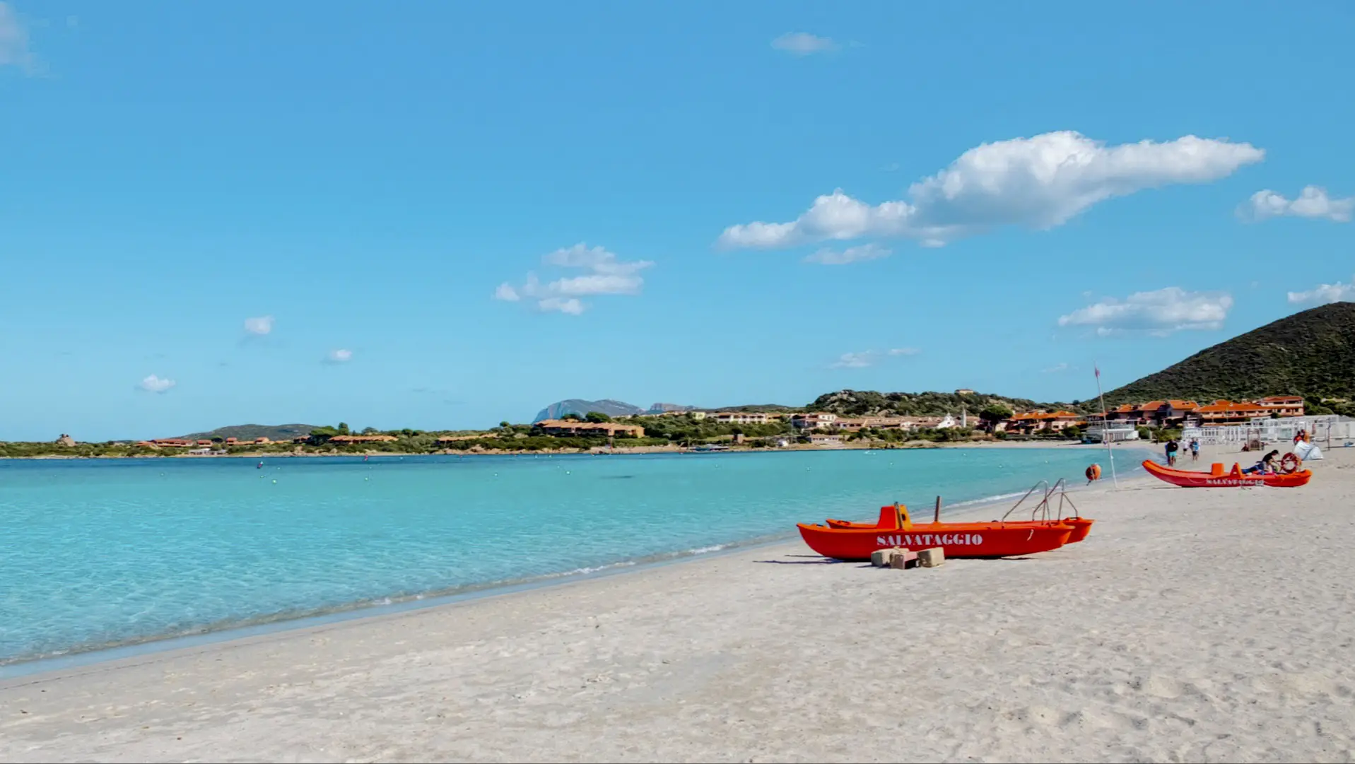 Blick zum Marinella-Strand in Gallura, Sardinien, Italien mit roten Booten am Strand sowie bei purem Sonnenschein.