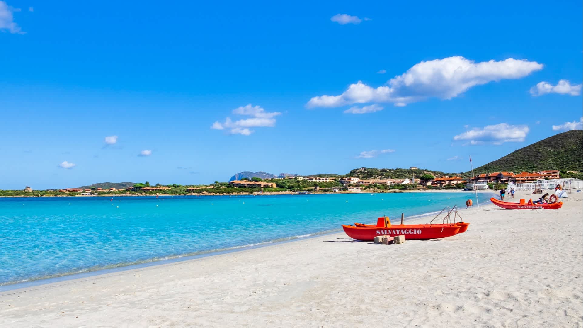 Blick zum Marinella-Strand in Gallura, Sardinien, Italien mit roten Booten am Strand sowie bei purem Sonnenschein.