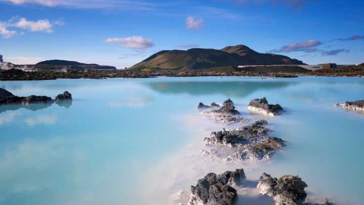 A large, blue natural spa in Iceland with mountains in the distance
