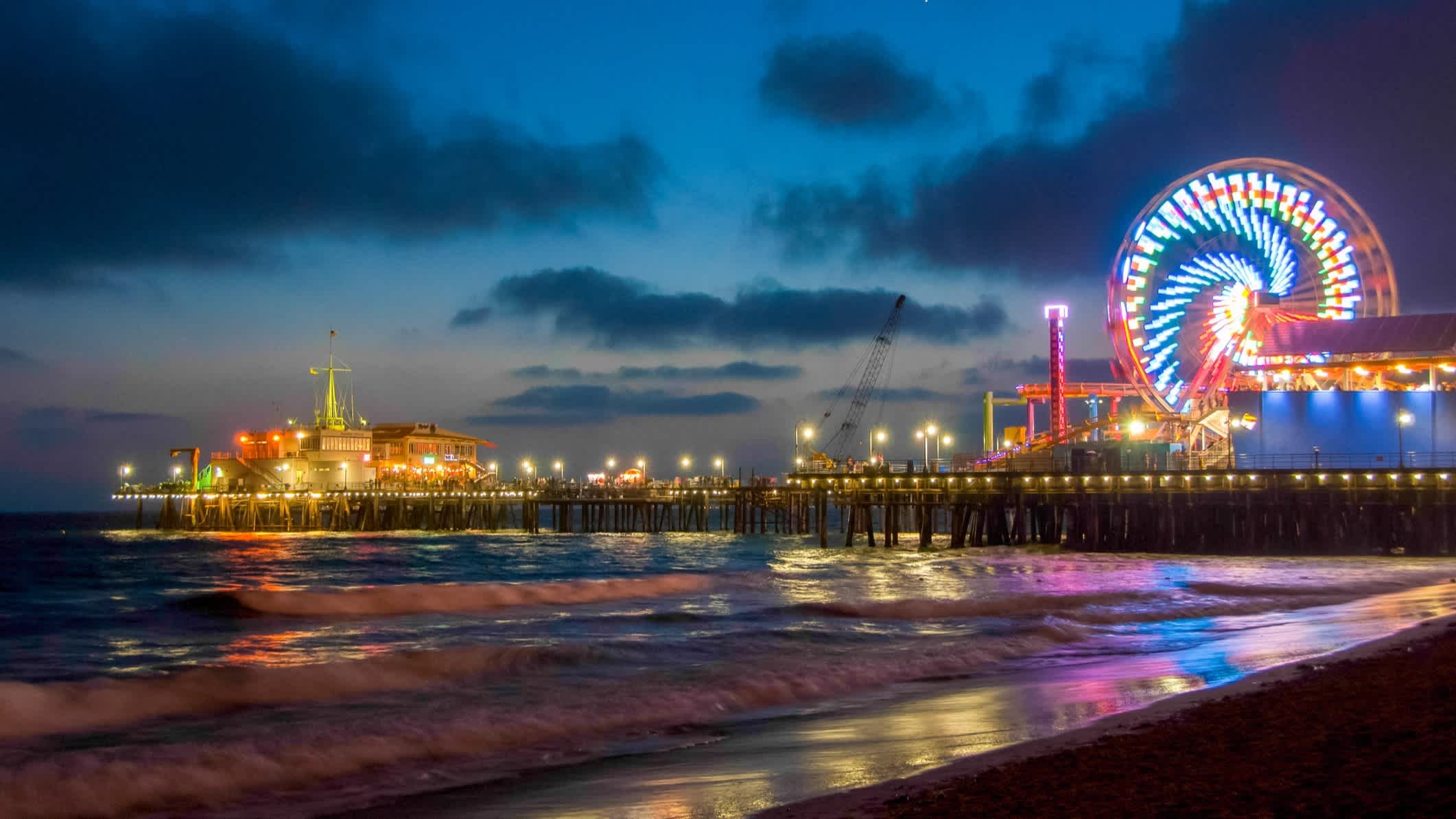Der Strand von Santa Monica, State Beach, Santa Monica, Kalifornien, USA bei Nacht und mit Blick auf das beleuchtete Santa Monica Peer mit buntem Riesenrad.