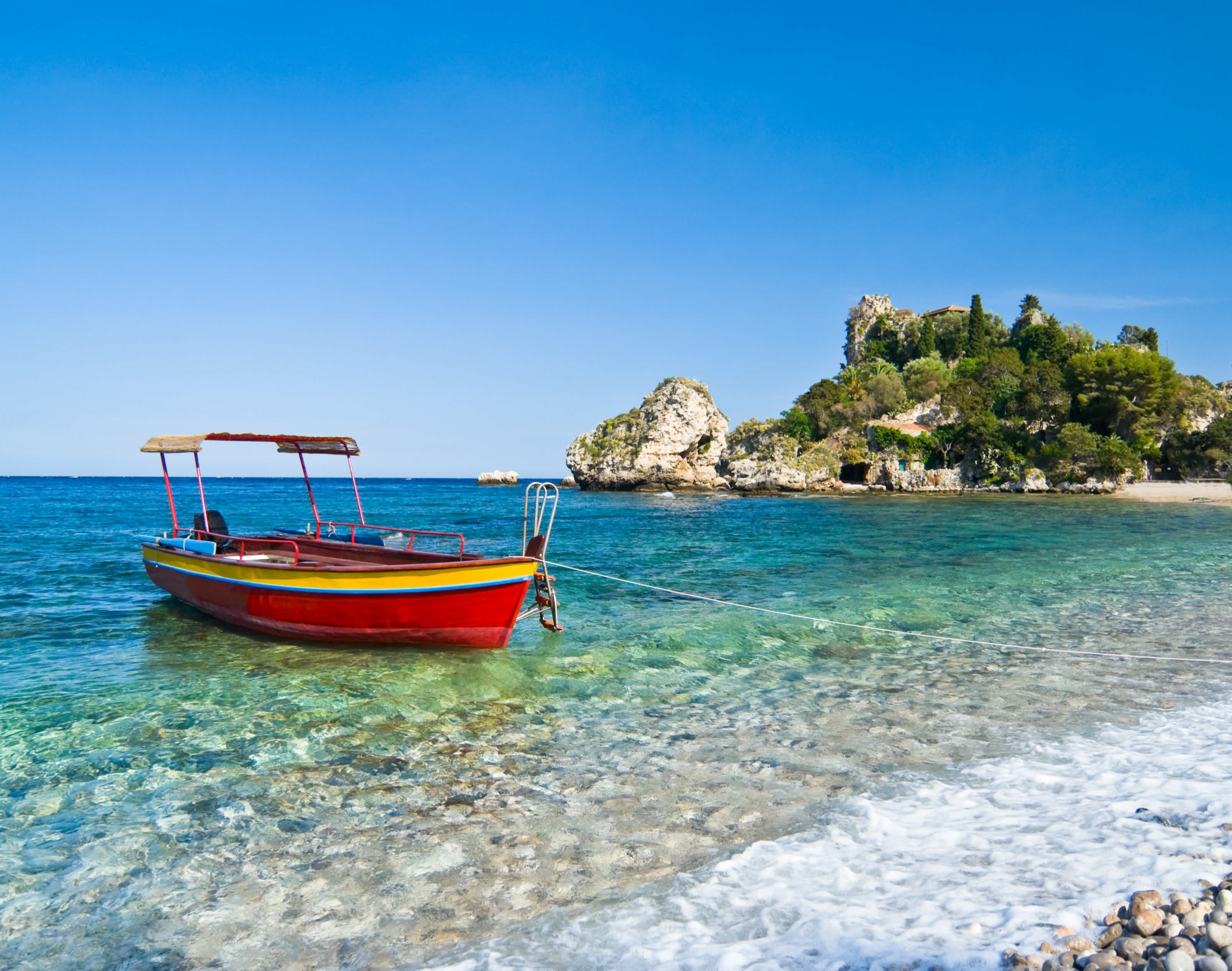 Bateau coloré au bord de l'eau sur l'Isola Bella, à Taormina, en Sicile, en Italie.