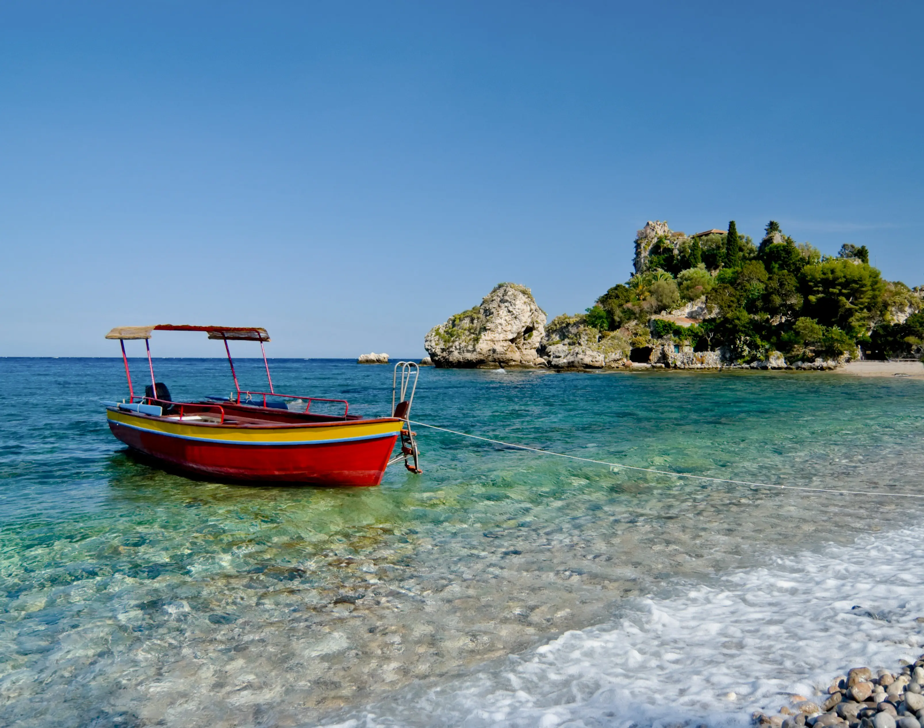 Bateau coloré au bord de l'eau sur l'Isola Bella, à Taormine, en Sicile, en Italie.