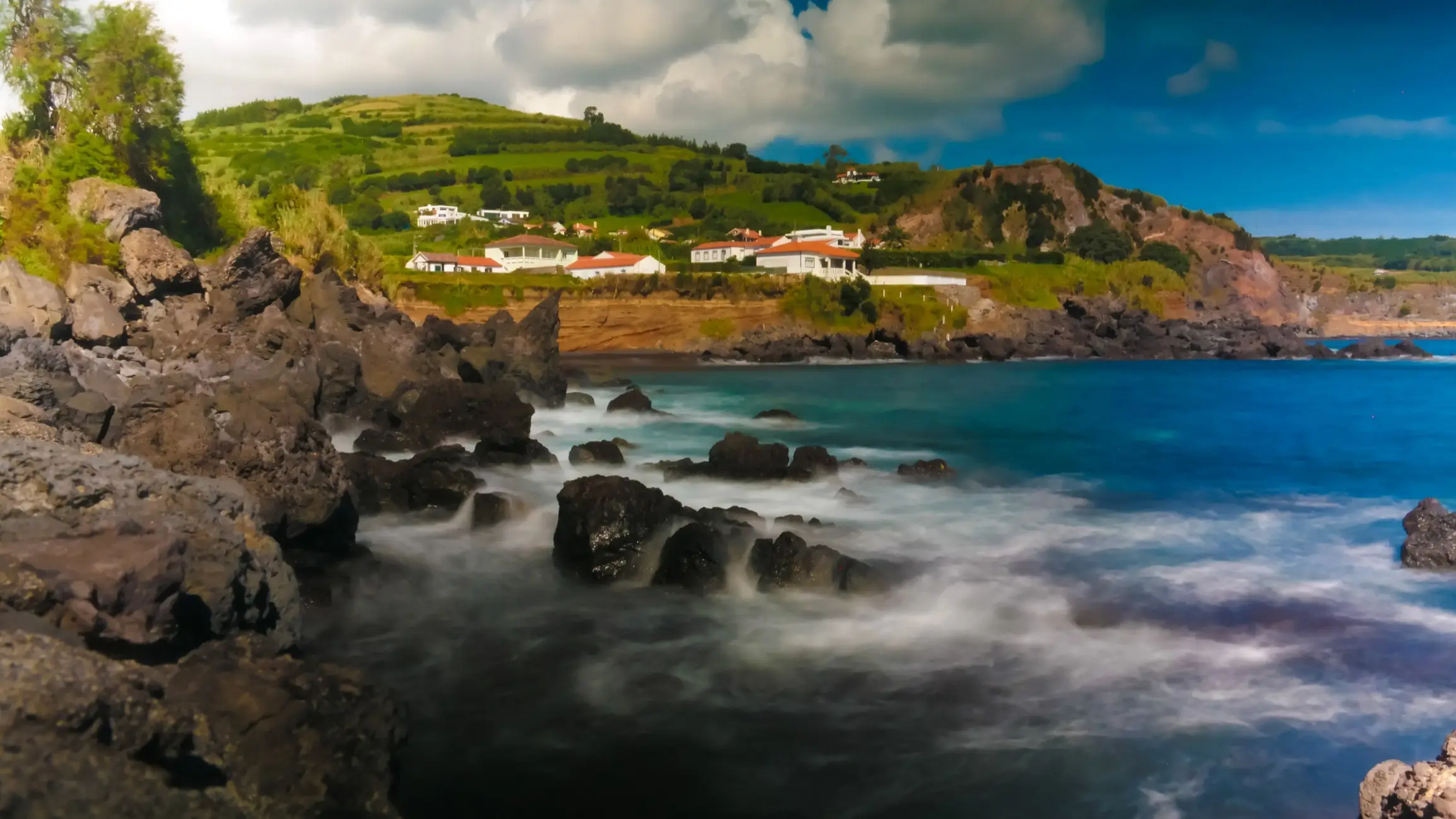 Portugal, Azoren, Almoxarife Landschaft der Praia Almoxarife, Faial Insel, Azoren, Portugal mit Blick auf grüne Hügel, Häuser sowie das nebelige Meer.