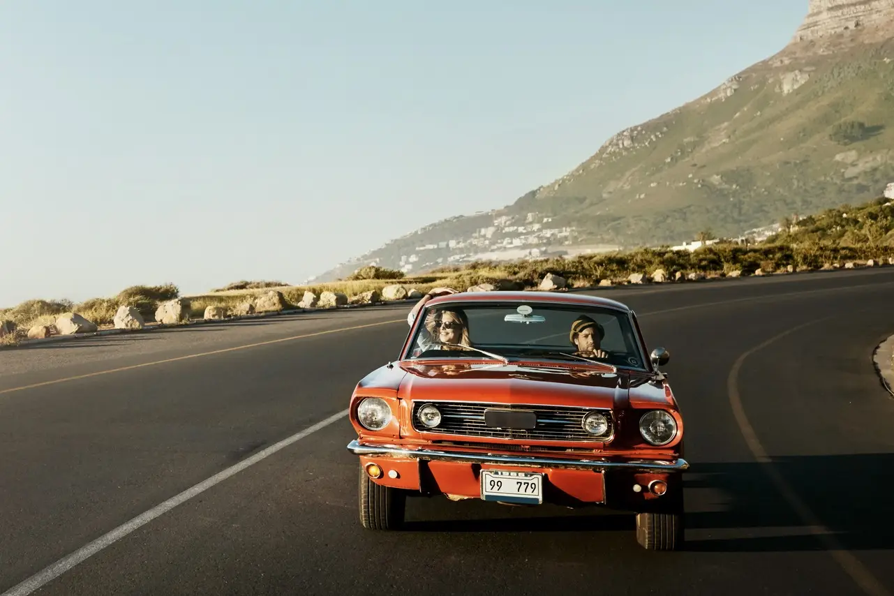 Roadtrip in Südafrika Rotes Auto fährt auf einer Straße in Südafrika