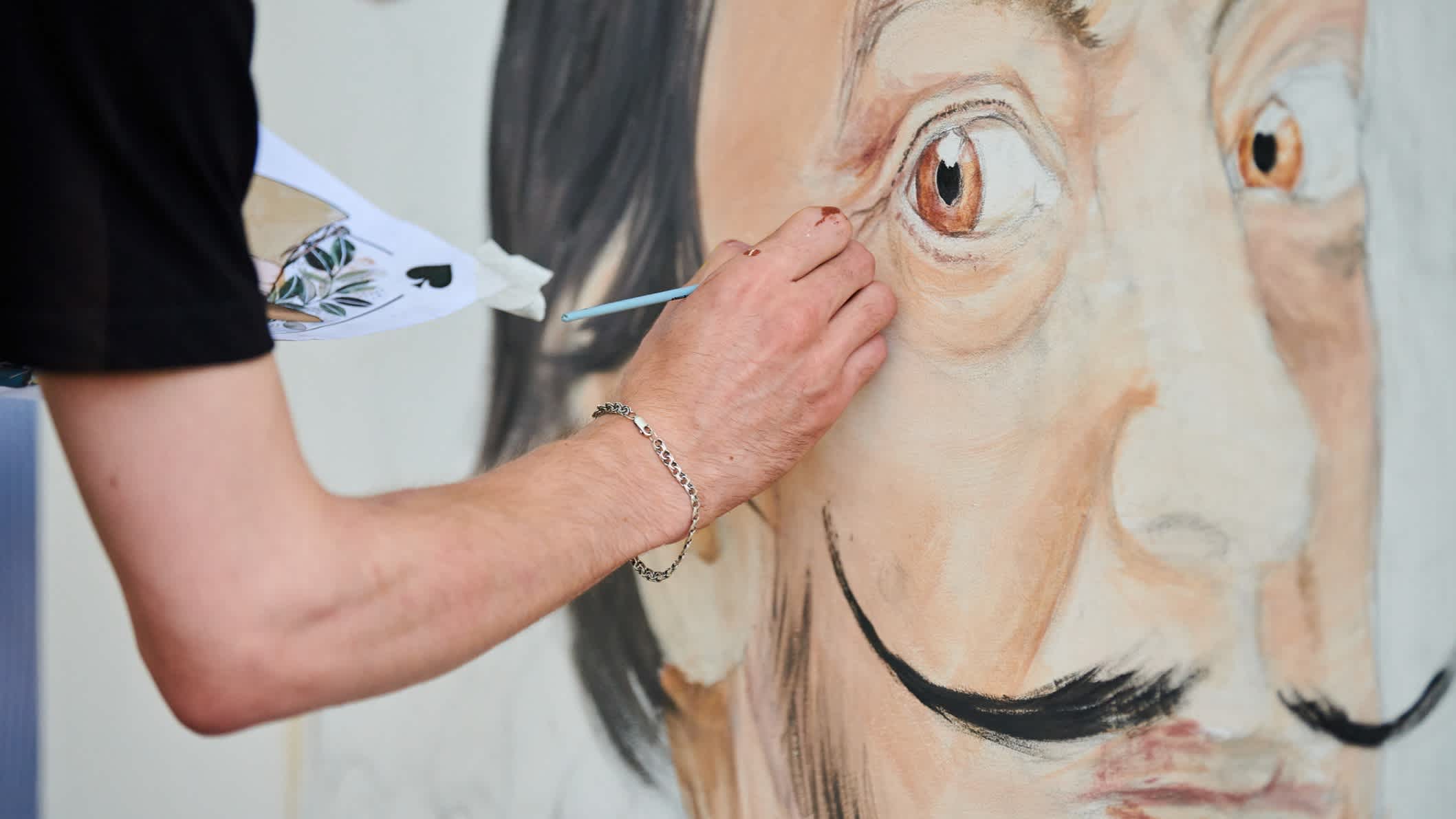 Junger Mann Künstler zeichnet mit Pinsel surrealer Mann Porträt auf weiße Leinwand Kunst Malerei Festival