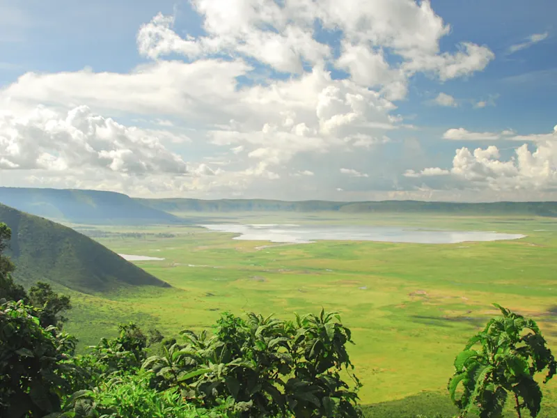 Weite Grasflächen im Ngorongoro-Krater in Tansania, umgeben von beeindruckender Natur