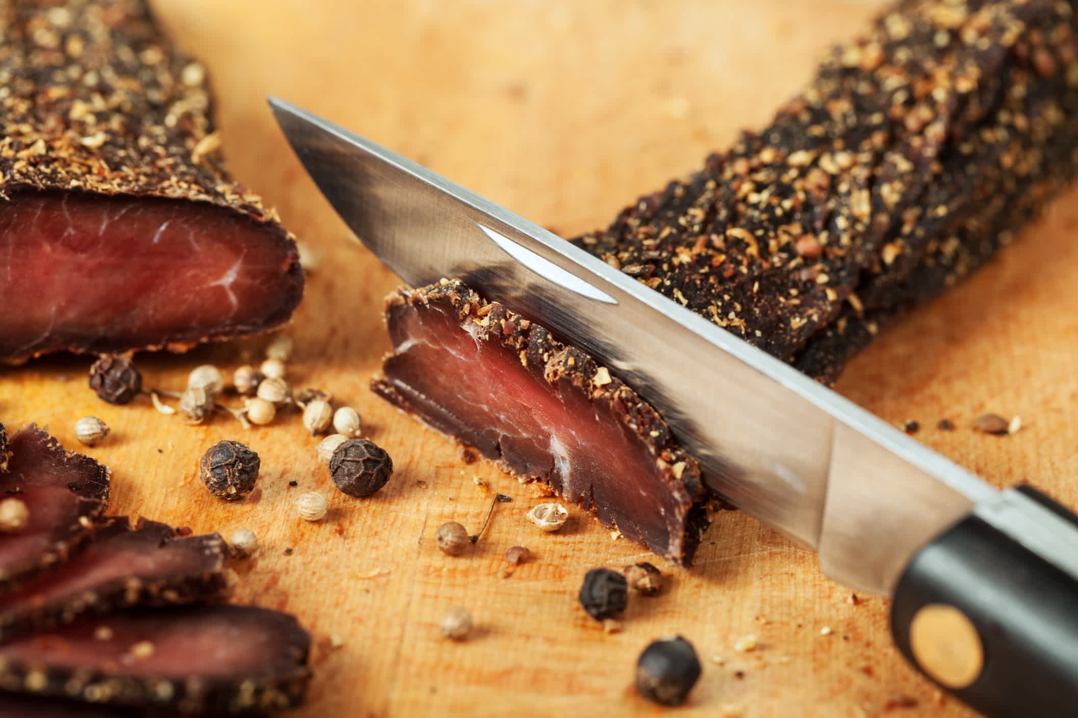 Biltong - traditionelle südafrikanische Delikatesse; rohes Rindfleisch mit Gewürzen und Salz an der Luft getrocknet; Taschenmesser mit Fleischstücken und Gewürzen;