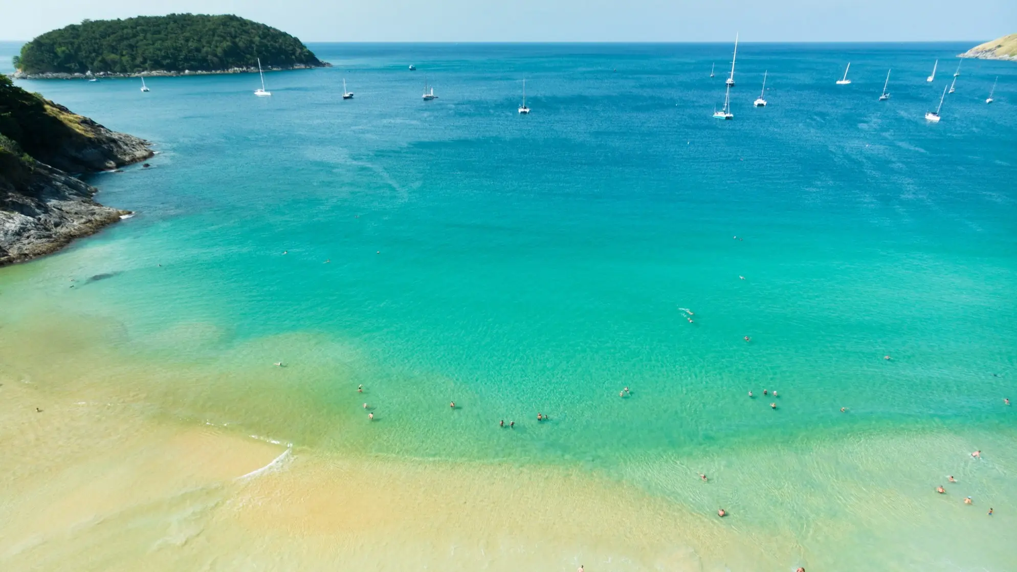 Thailand, Phuket, Nai Harn Beach Der Nai Harn Beach mit Sandstrand und cyanblazem Meer, Booten und eine Insel im Hintergrund.