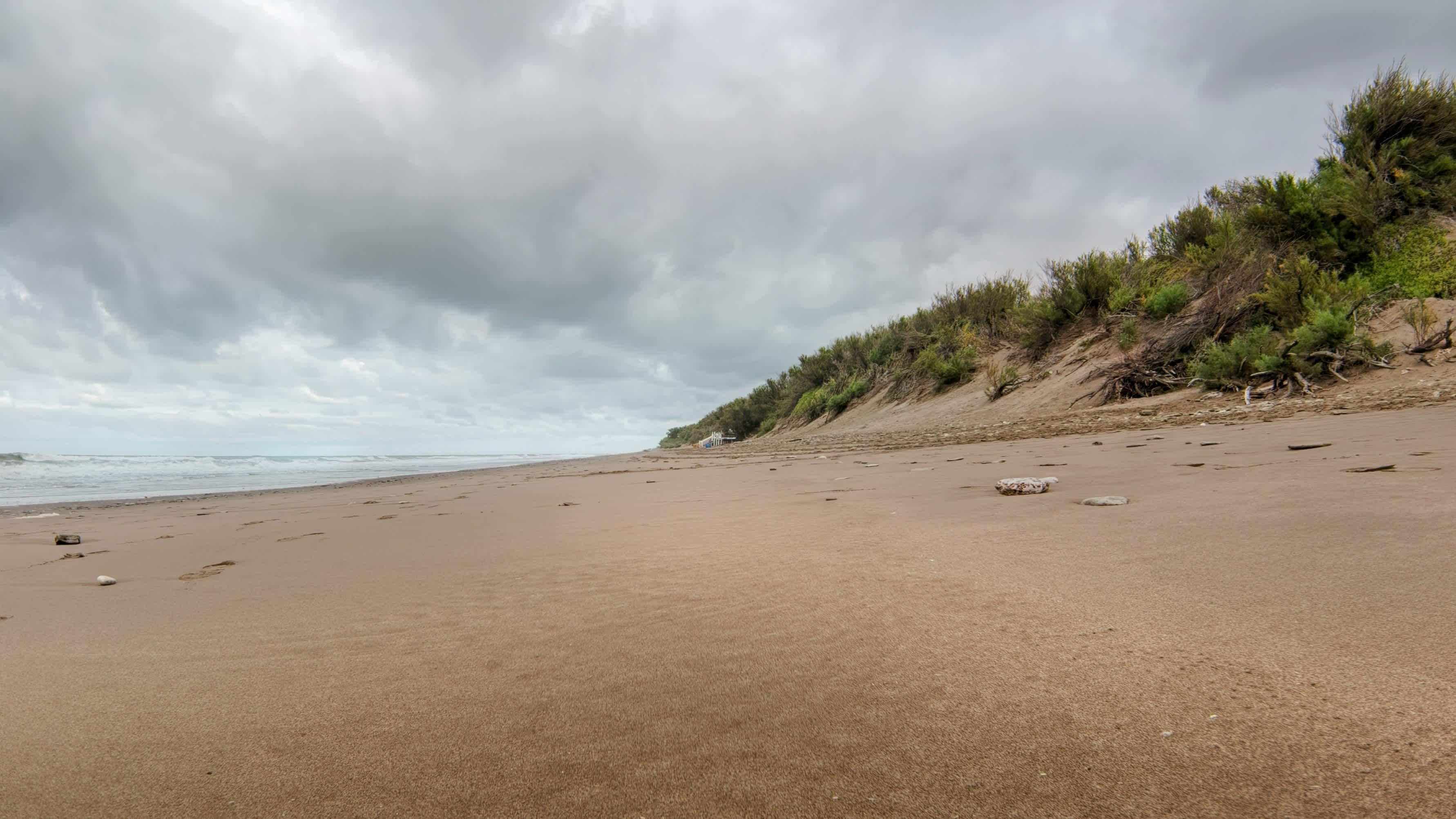 plage déserte dunes de sable végétation ciel gris nuages mer en Argentine