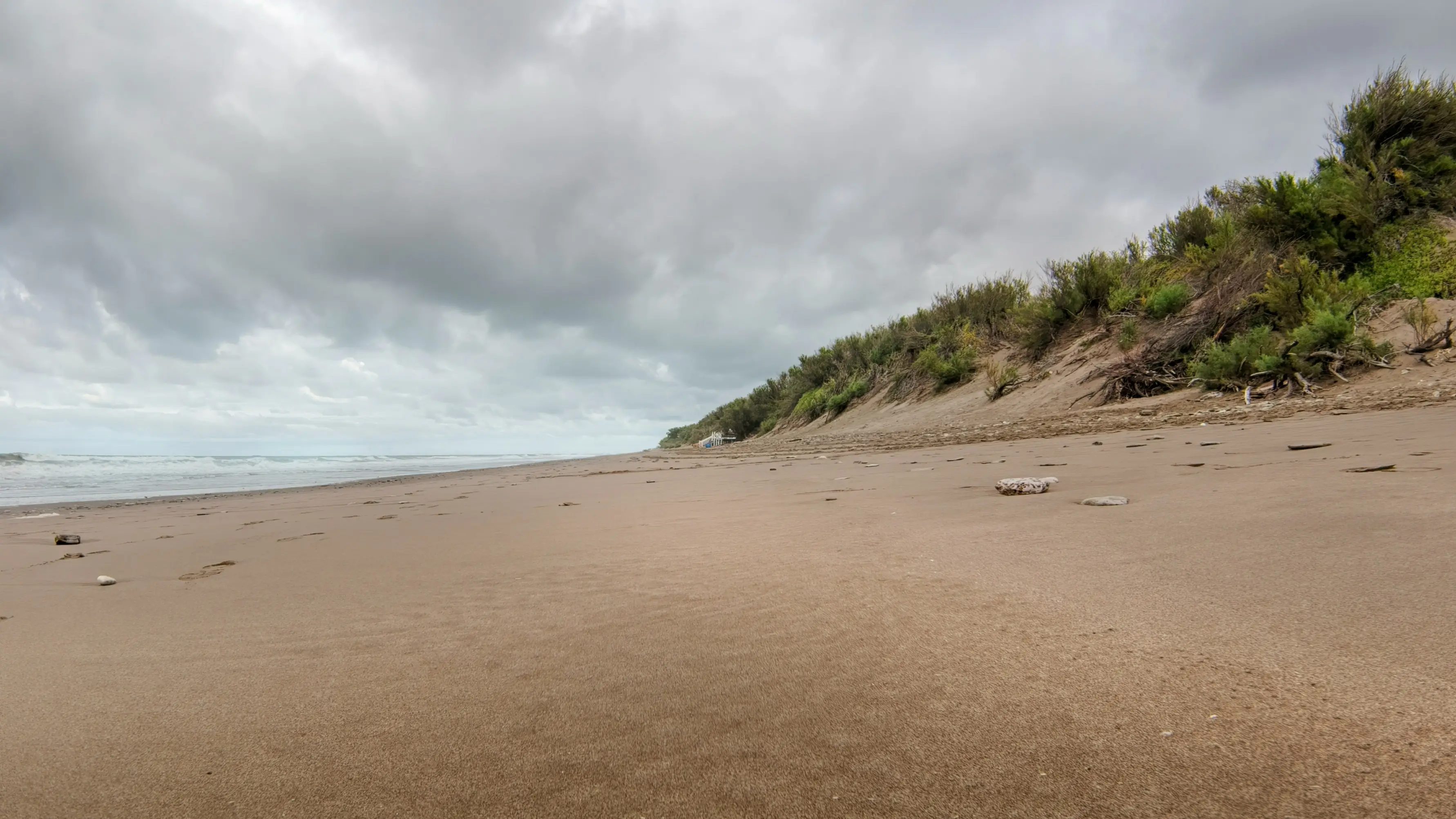 Orense, Argentina einsamer Strand Sanddünen Vegetation grauer Himmel Wolken Meer