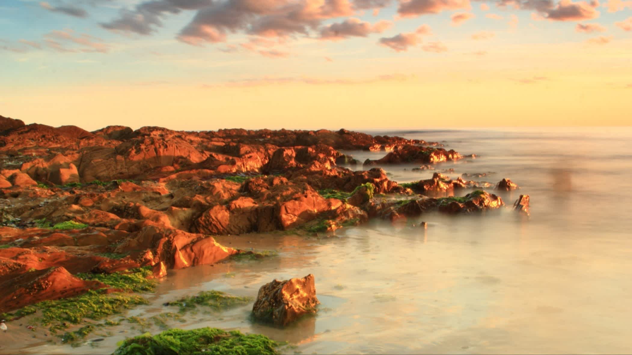 Strand von Los Botes bei Sonnenuntergang, La Paloma, Uruguay mit Felsen im Bild und bei Sonnenuntergang.

