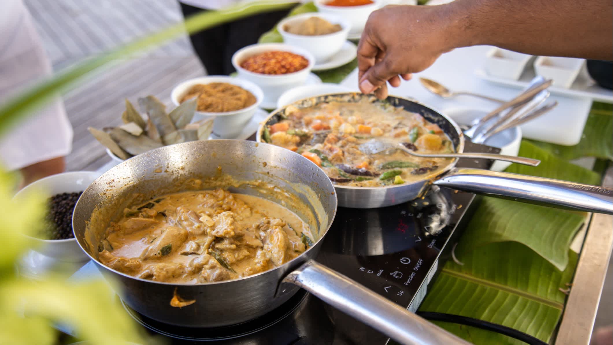 Maledivisches Thunfischcurry in Stahlpfanne in der Küche mit Kokoscrememilch und Gewürzen