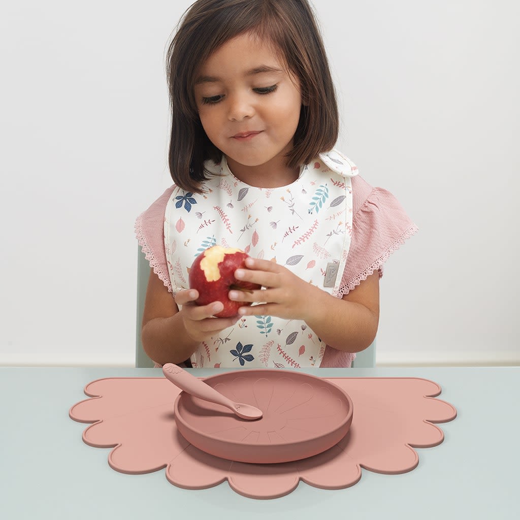 kid eating an apple in front of her plate